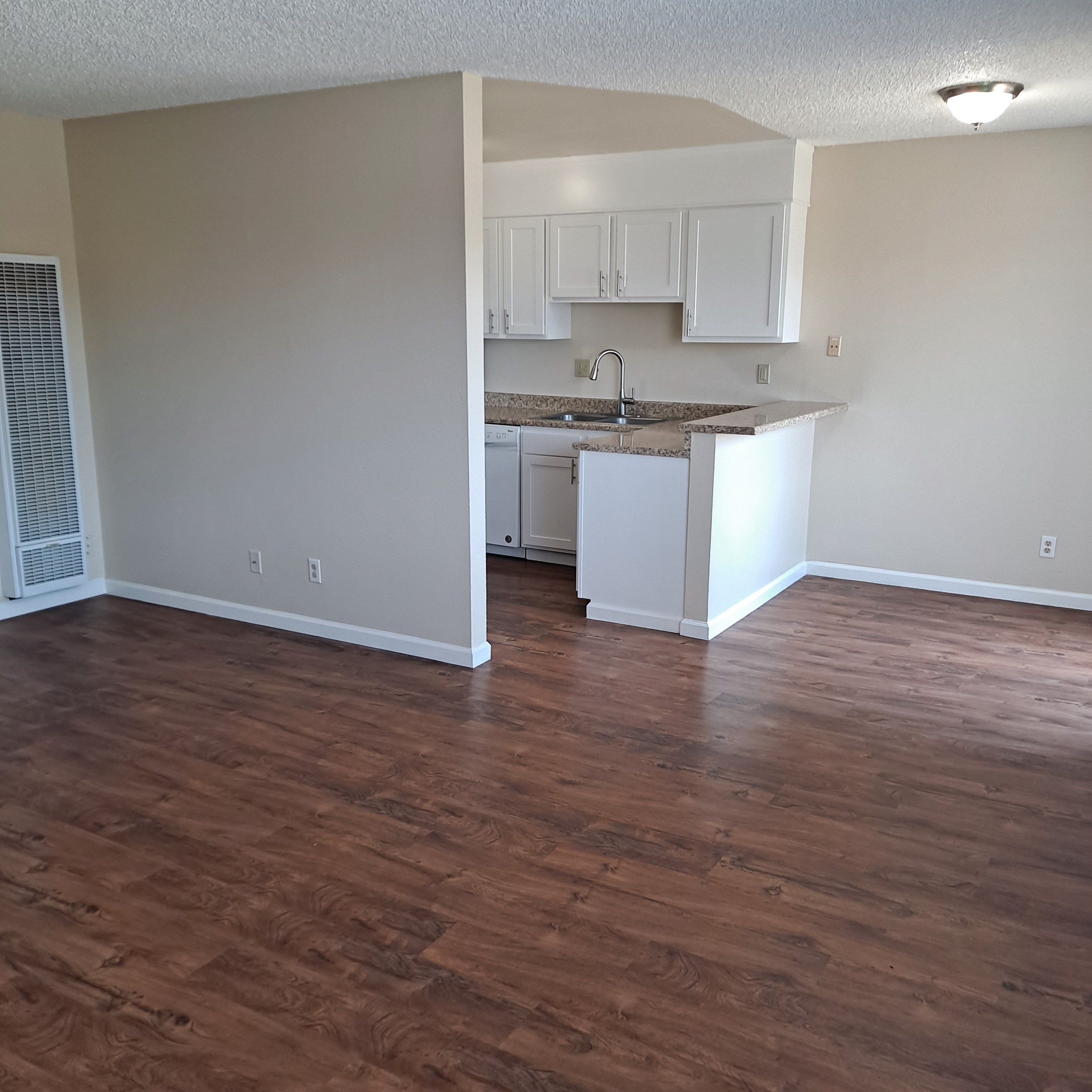 A kitchen with white cabinets and a brown floor.