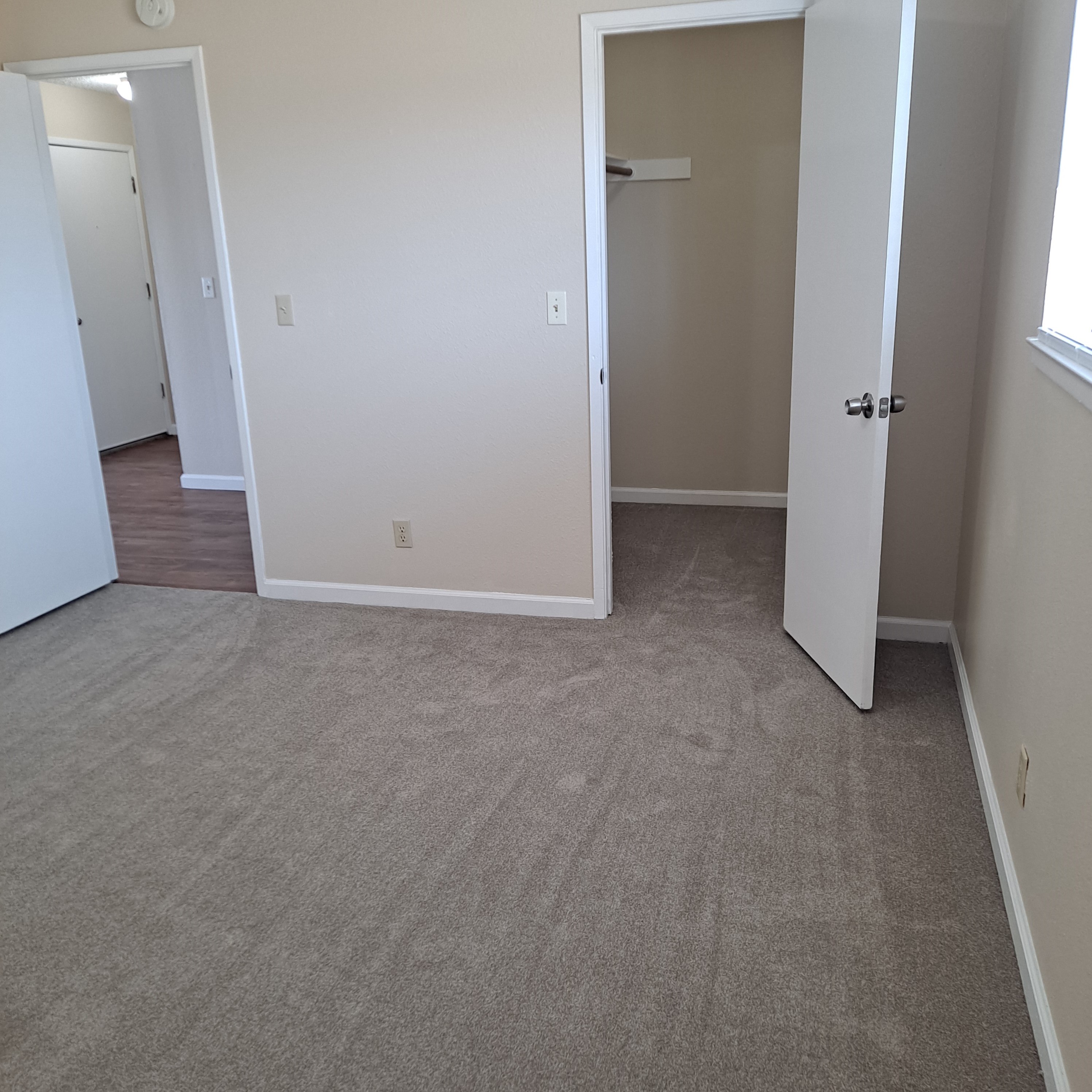 A room with a carpeted floor and two doors.