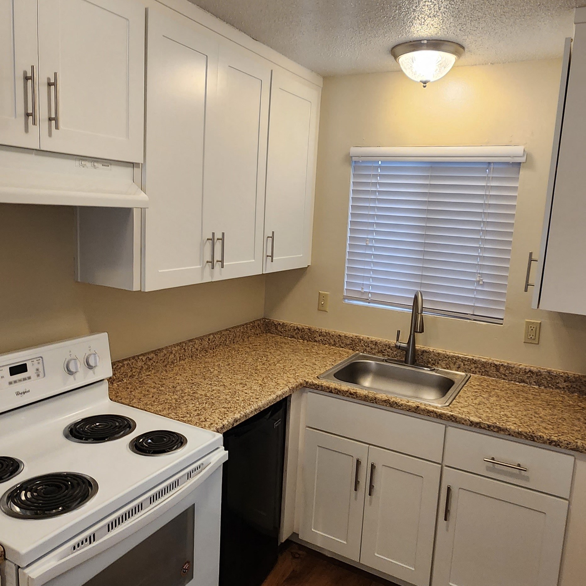 a kitchen with white appliances and granite counter tops and white cabinets