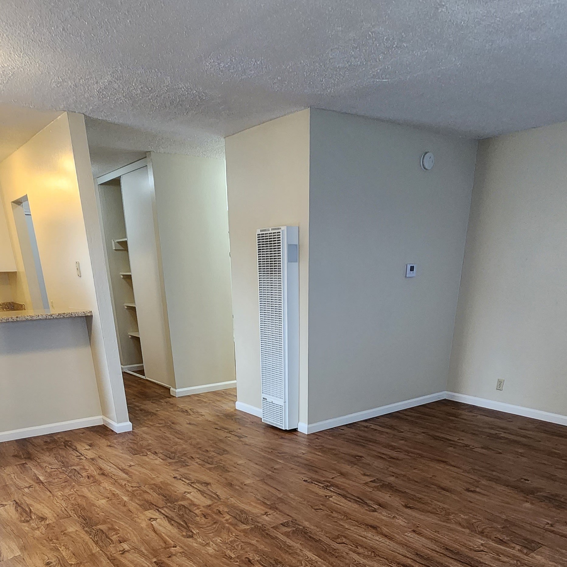 an empty living room with a heater in the corner