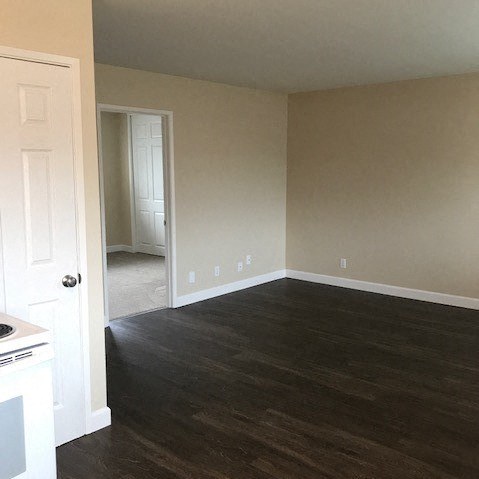 an empty living room with wood floors and a white door