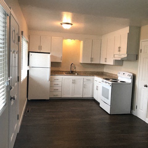 a white kitchen with a stove and a refrigerator