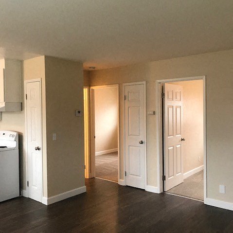 an empty living room with three doors and a kitchen