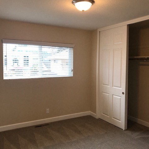 an empty room with a window and a closet