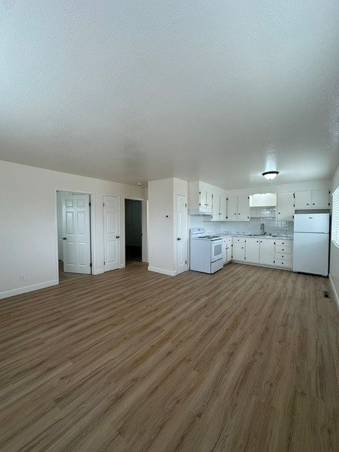 A kitchen with white appliances and wooden floors.