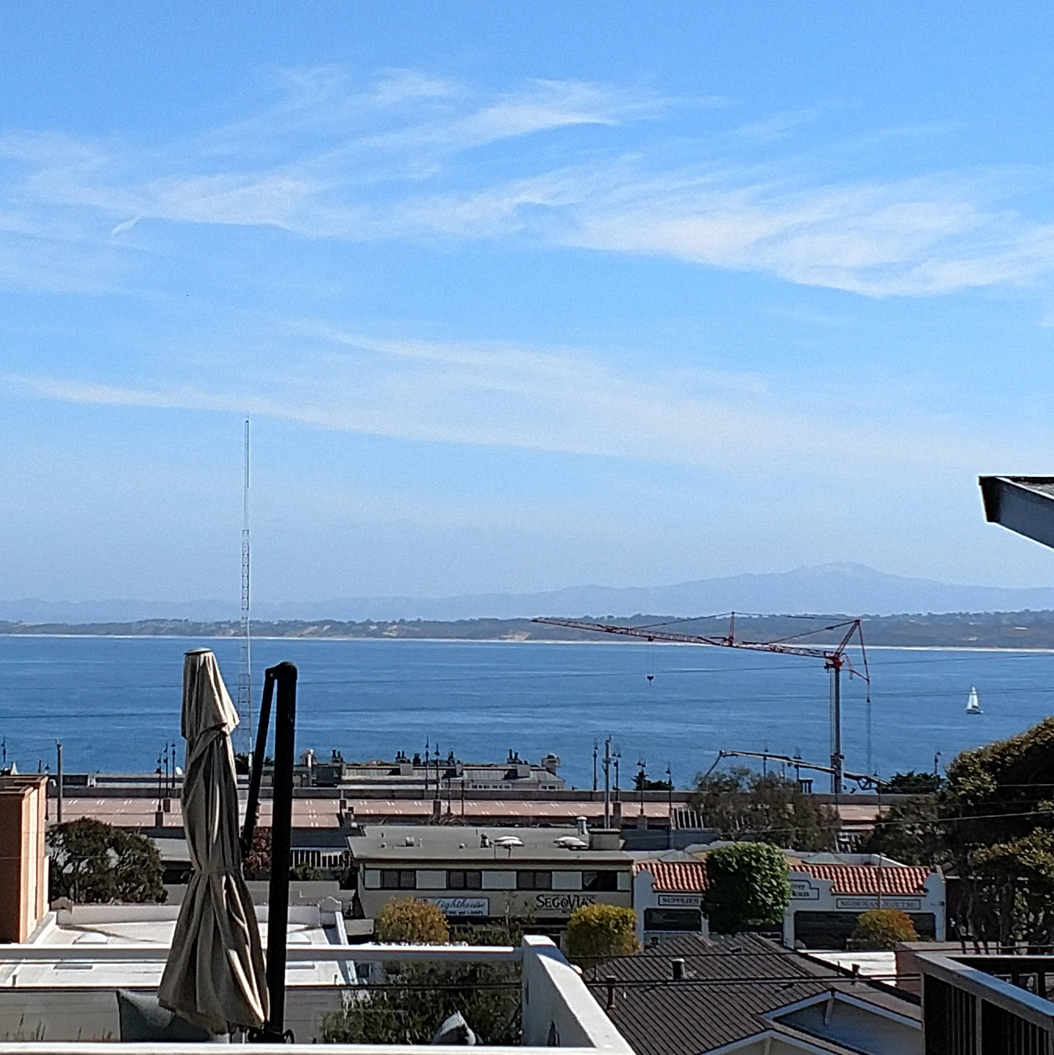 a view of the ocean from the balcony of a house with an umbrella