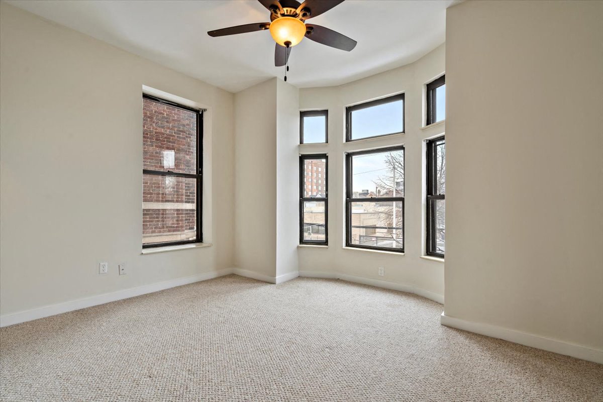 an empty room with a ceiling fan and five windows
