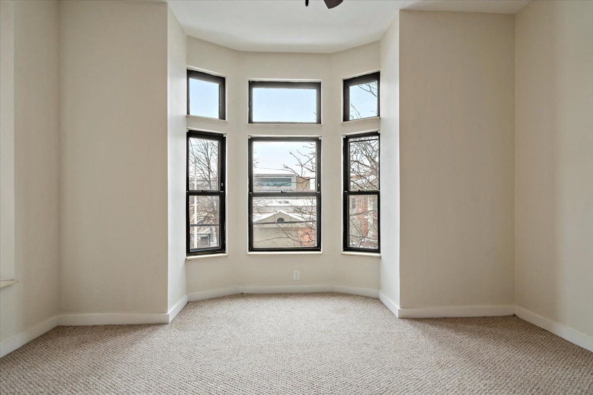 an empty room with four windows and a ceiling fan