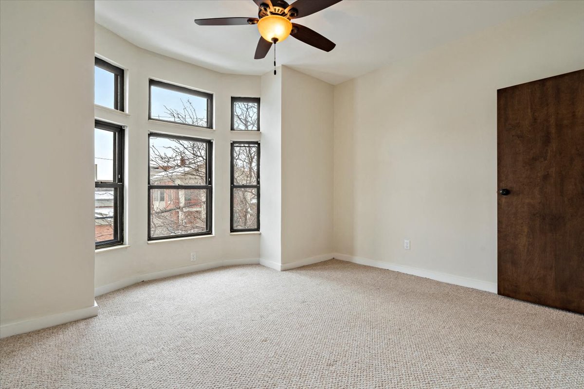 an empty bedroom with a ceiling fan
