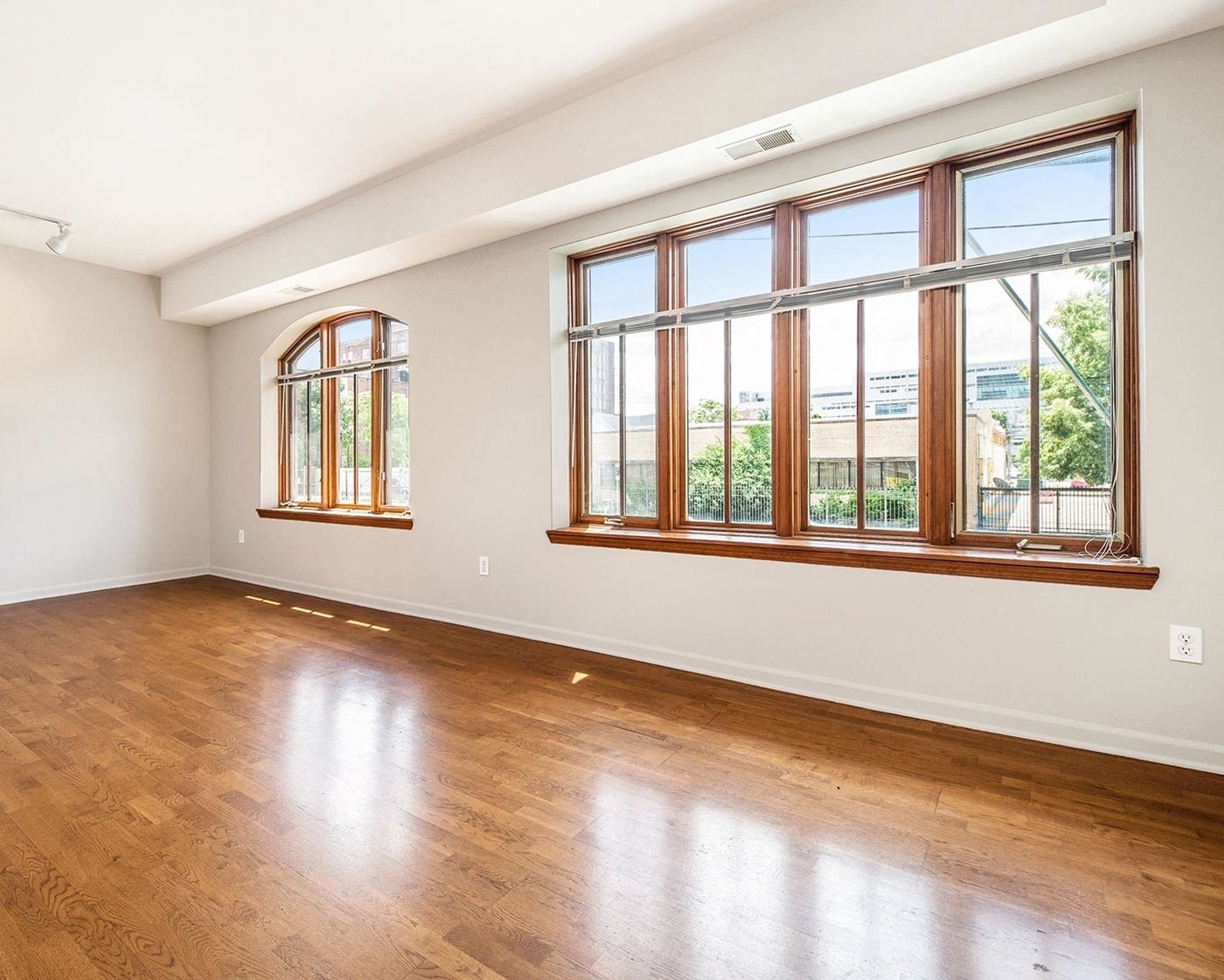 an empty living room with hardwood floors and large windows