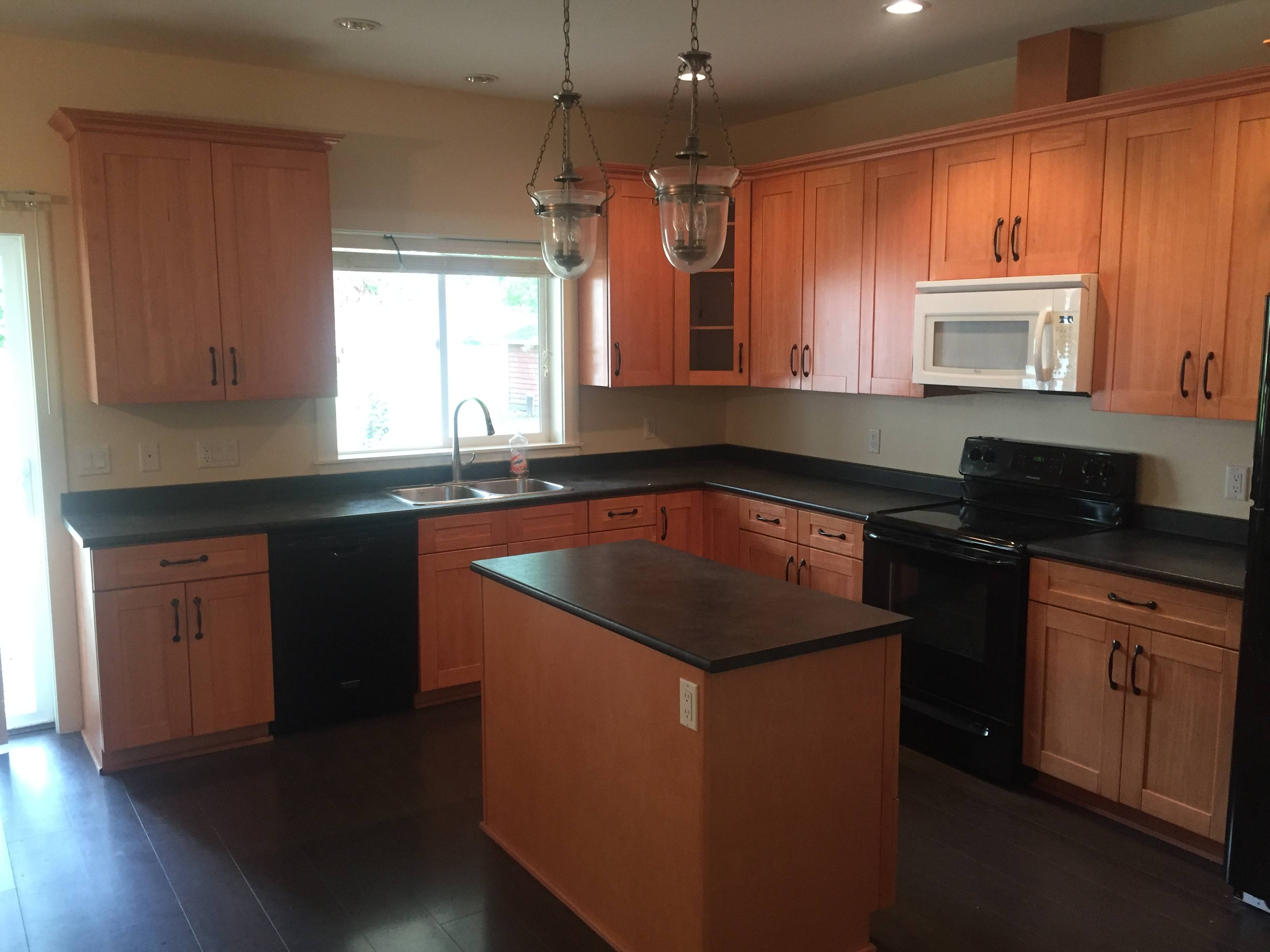 A kitchen with wooden cabinets and black countertops.