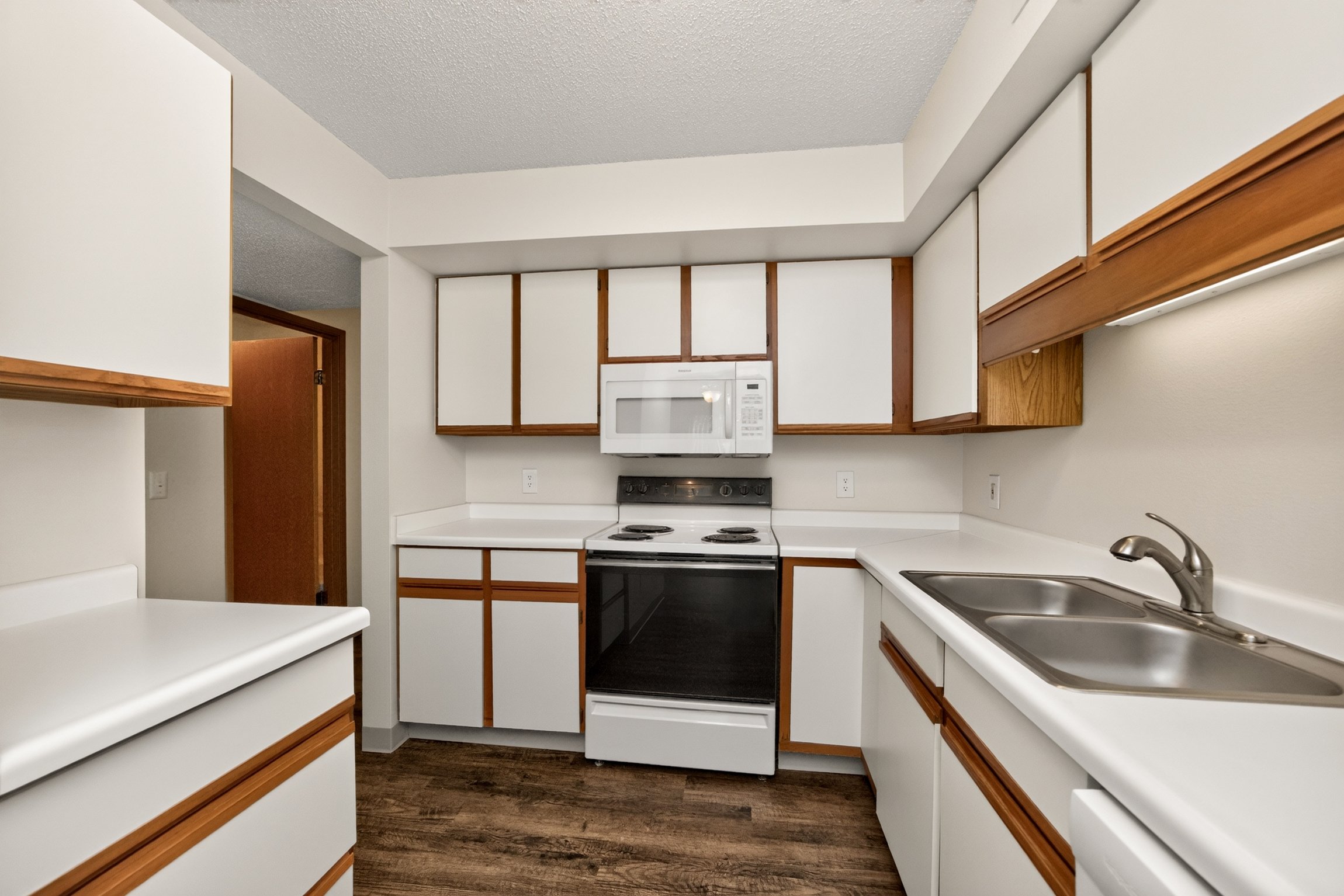 A kitchen with white cabinets and a wood trim.