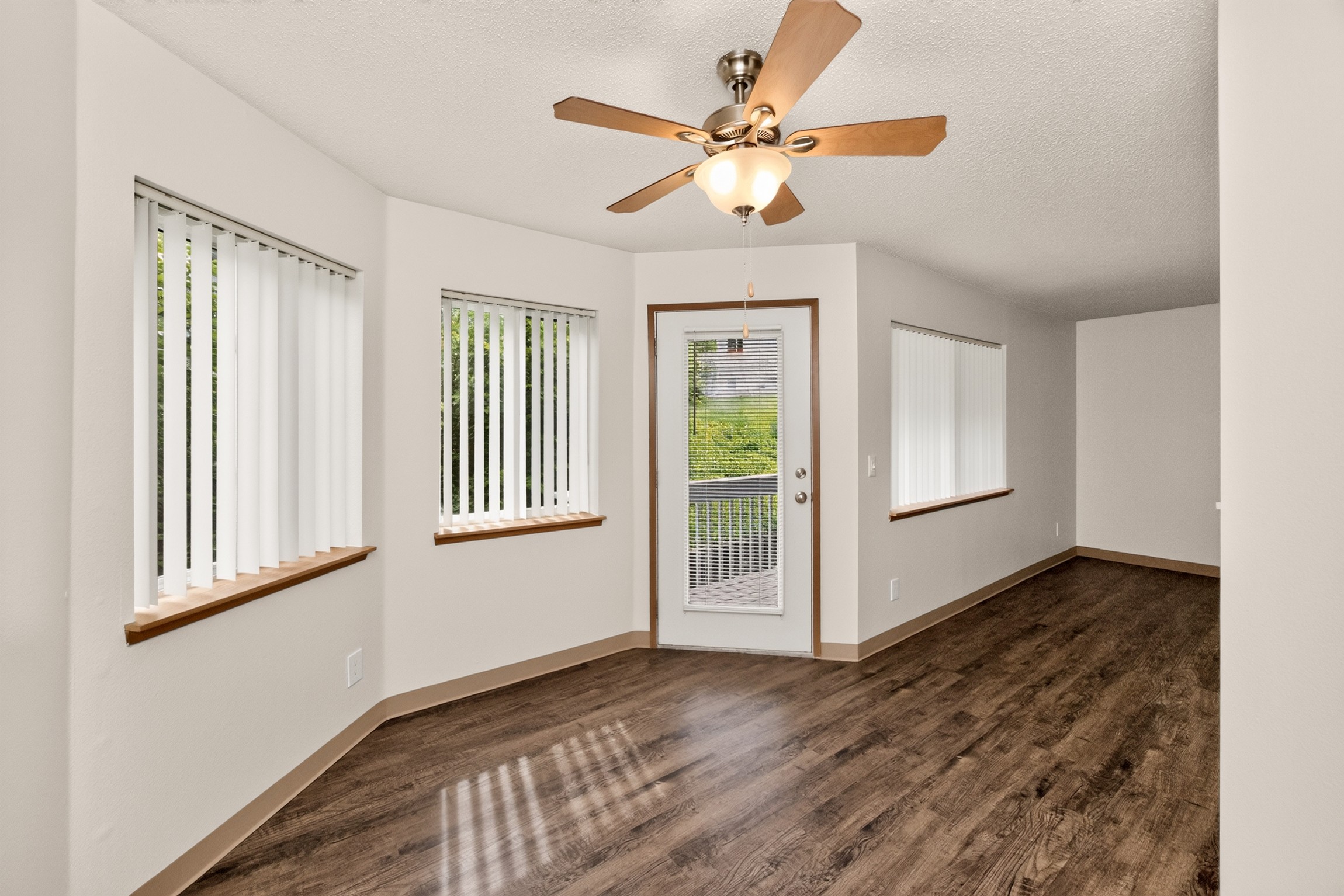 A room with a ceiling fan and wooden flooring.