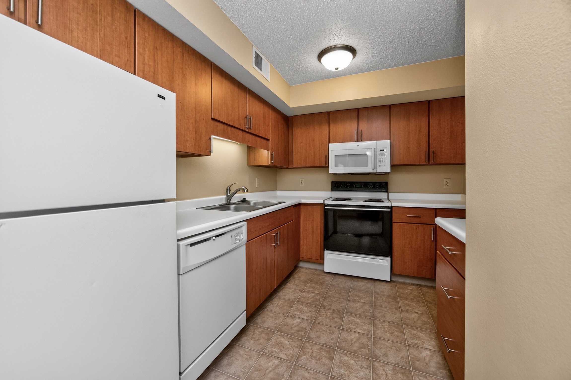 A kitchen with a white refrigerator, brown cabinets, and a white stove top oven.
