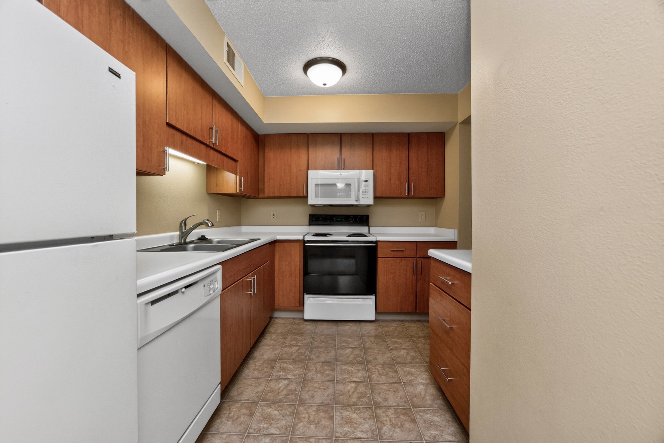 A kitchen with white appliances and brown cabinets.