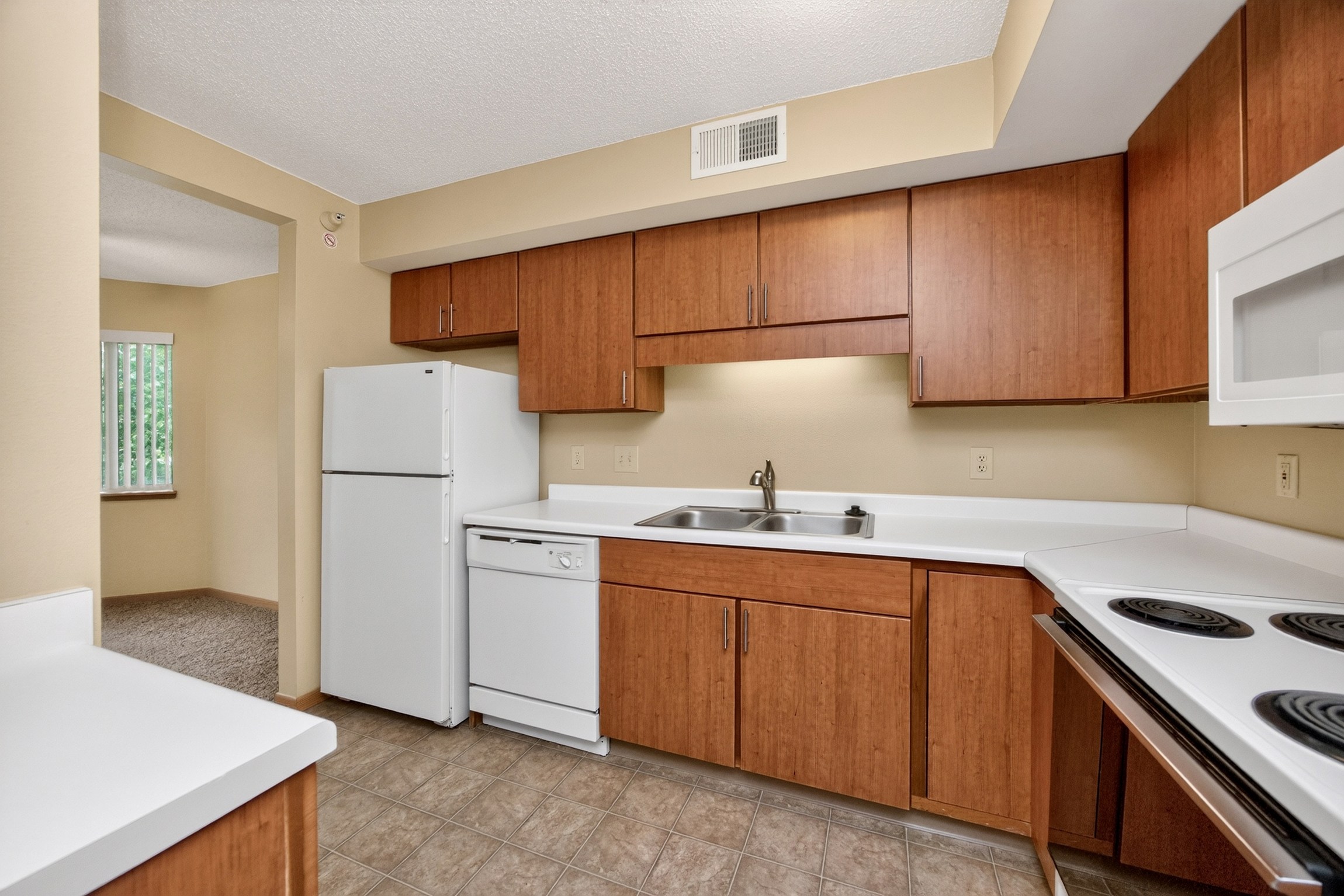 A kitchen with white appliances and wooden cabinets.