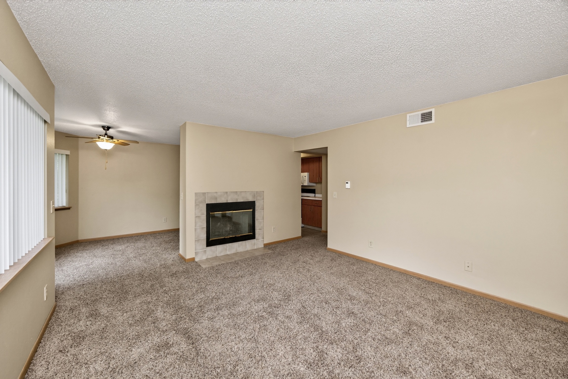 A living room with a fireplace and a ceiling fan.