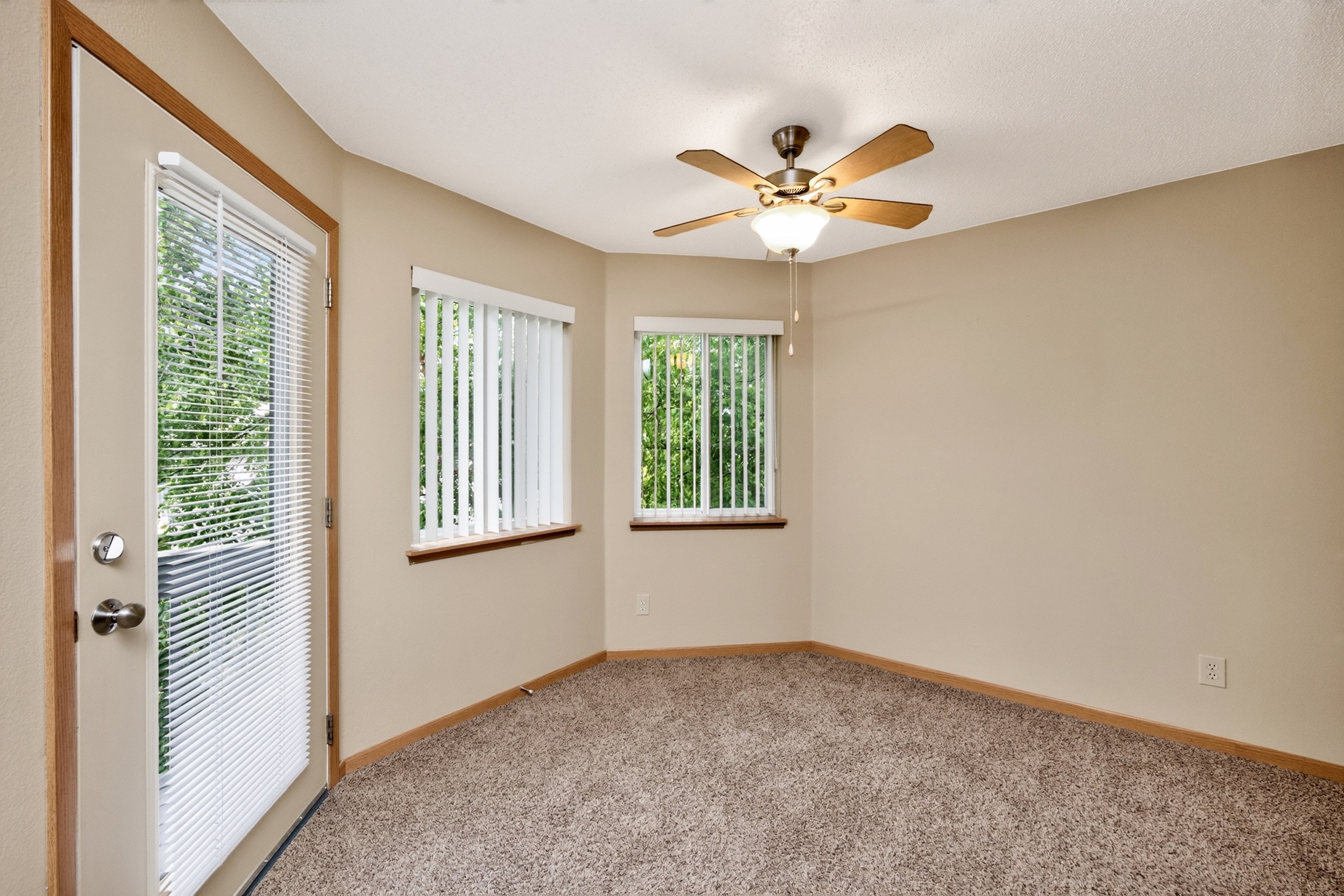 A room with a ceiling fan and two windows.
