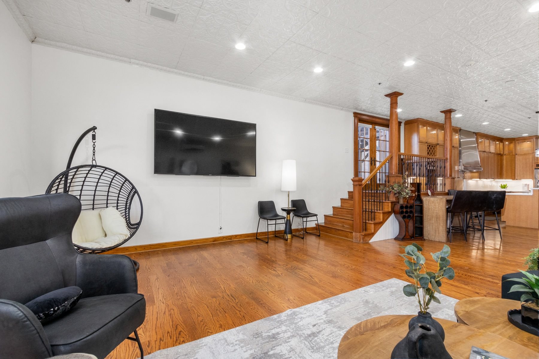 A living room with a black leather chair and a wooden floor.