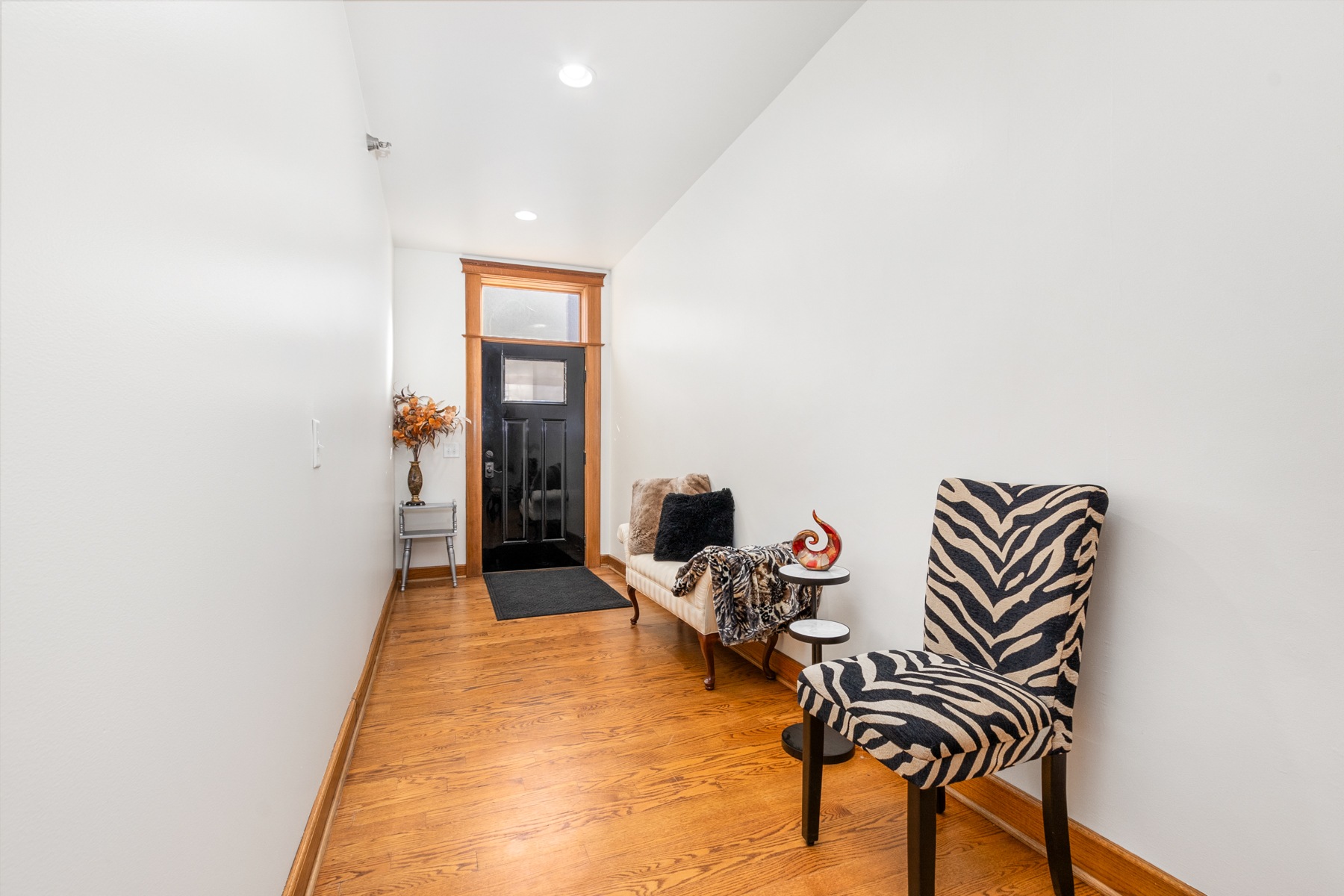 A zebra print chair sits in a hallway with a black door in the background.