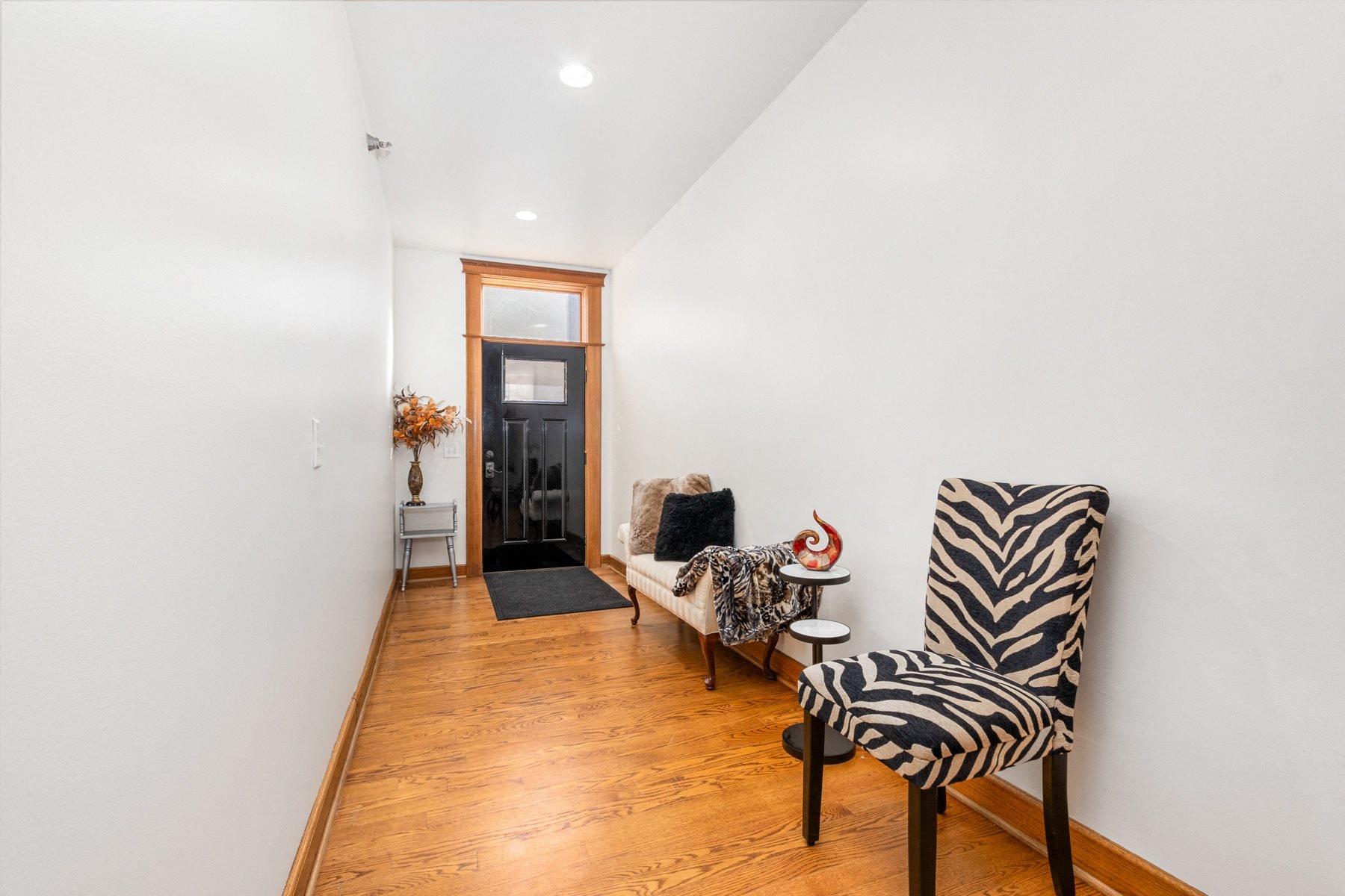 A zebra print chair sits in a hallway with a black door in the background.
