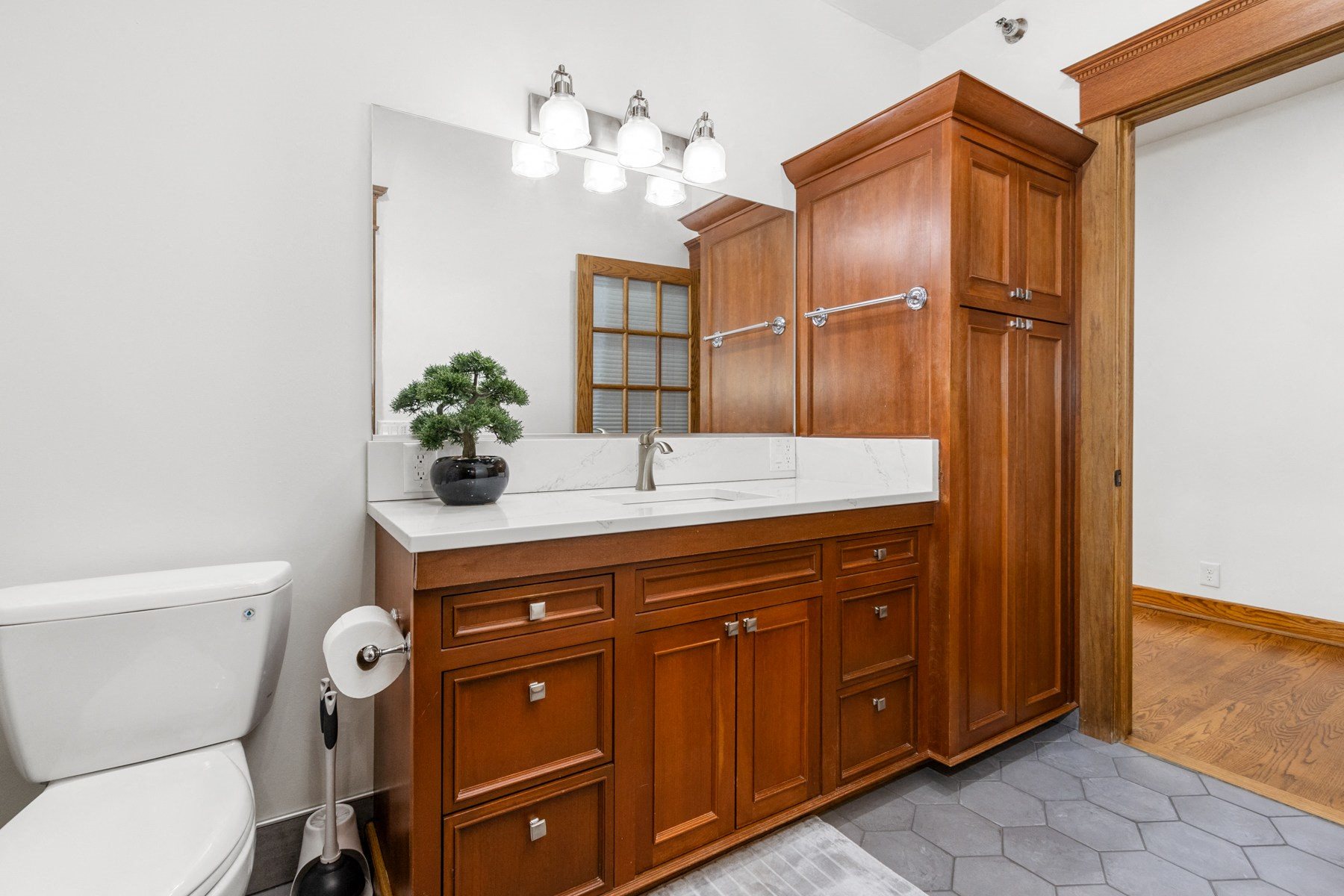 A bathroom with a white toilet, wooden cabinets, and a sink.