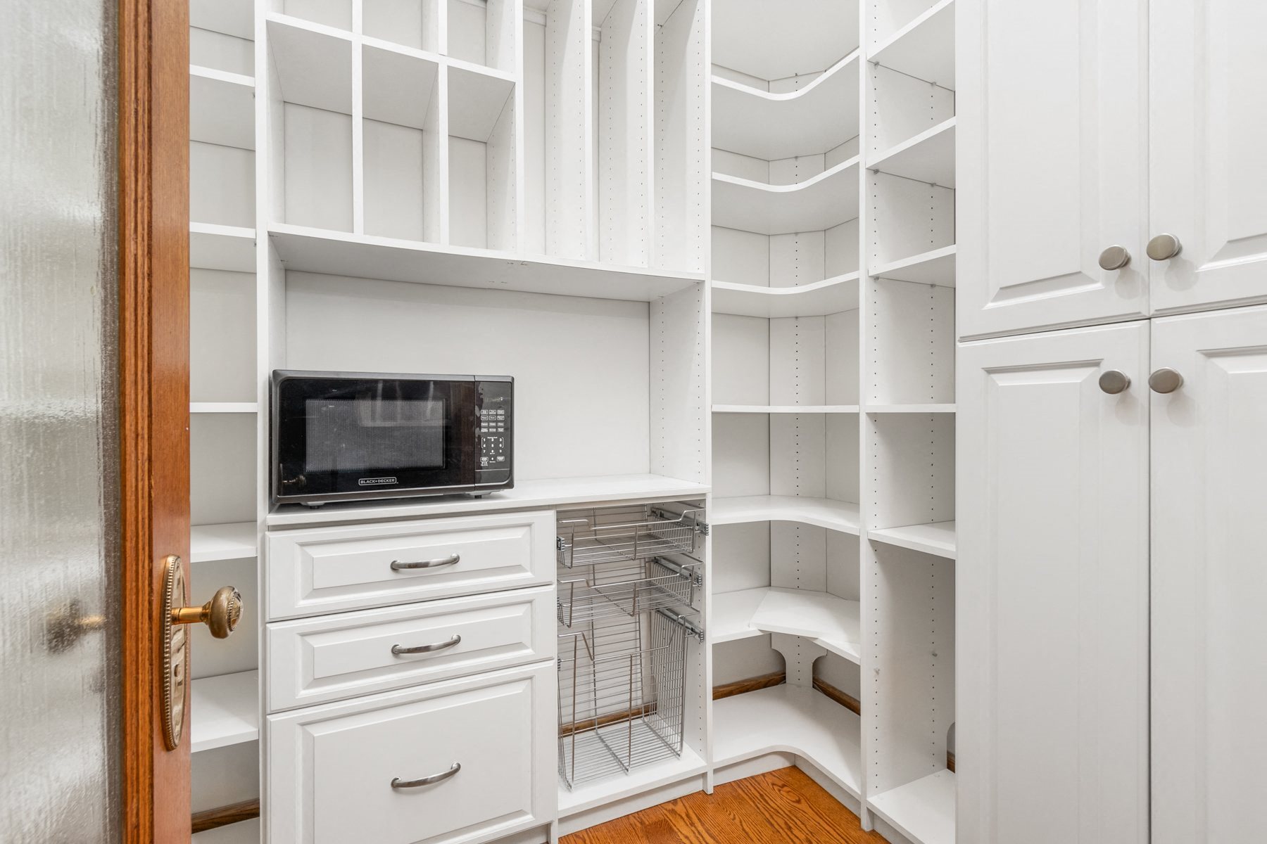 A kitchen pantry with a microwave on the counter.