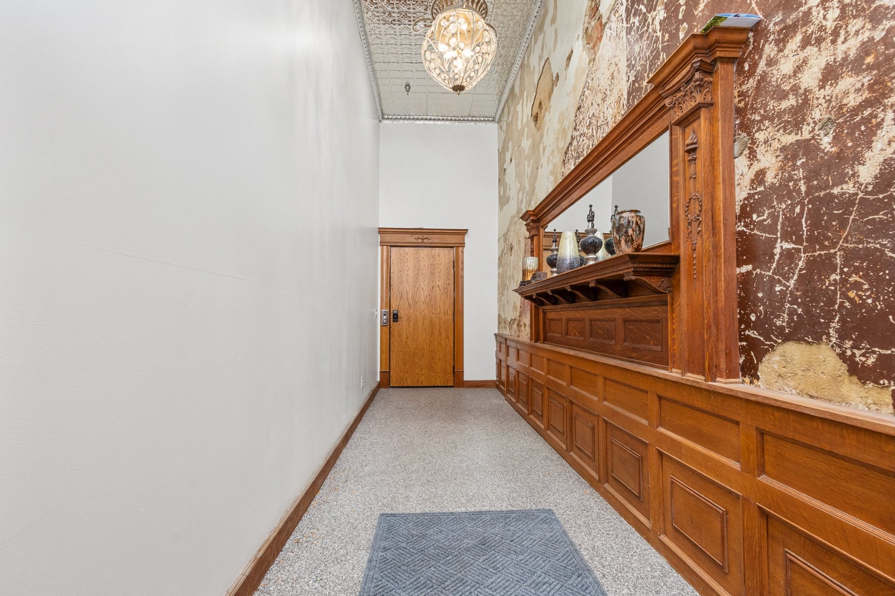 A hallway with a wooden door and a mirror on the wall.