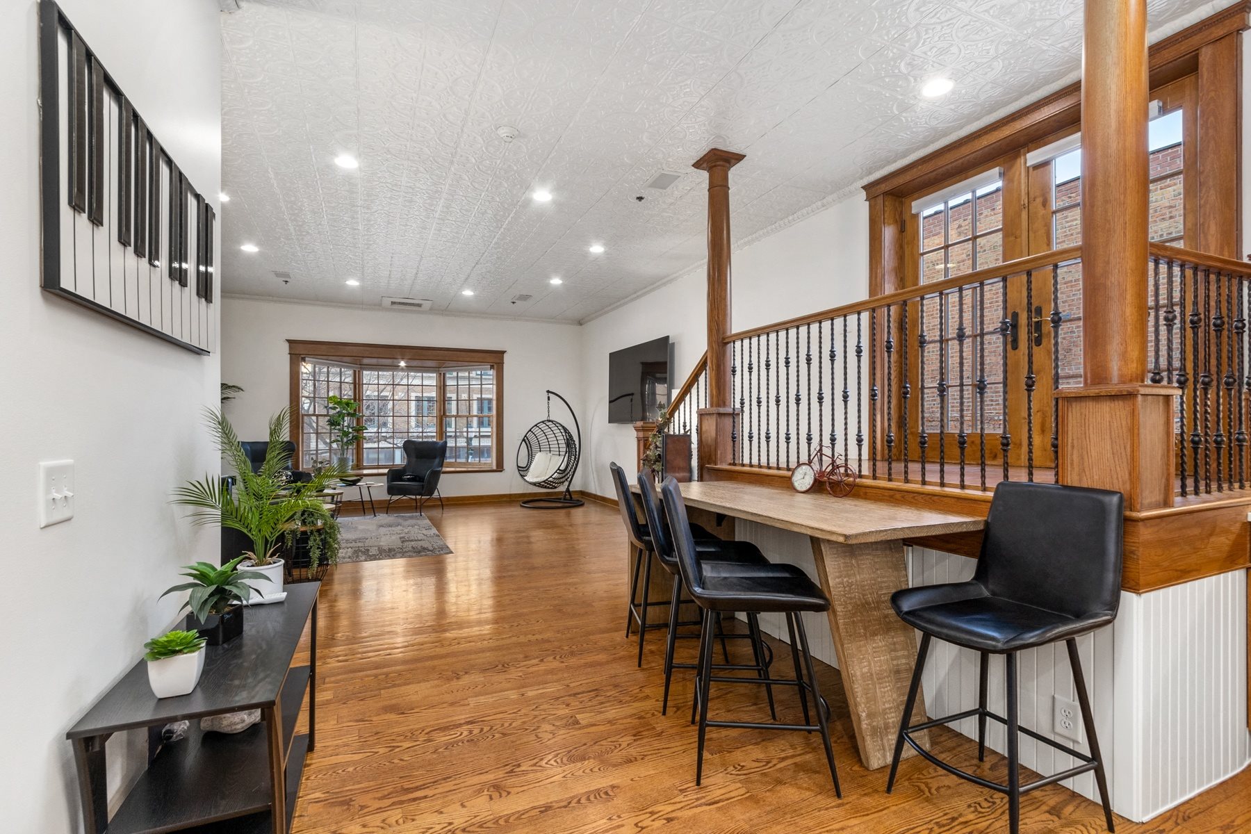 A room with a piano on the wall and a bar area with stools.