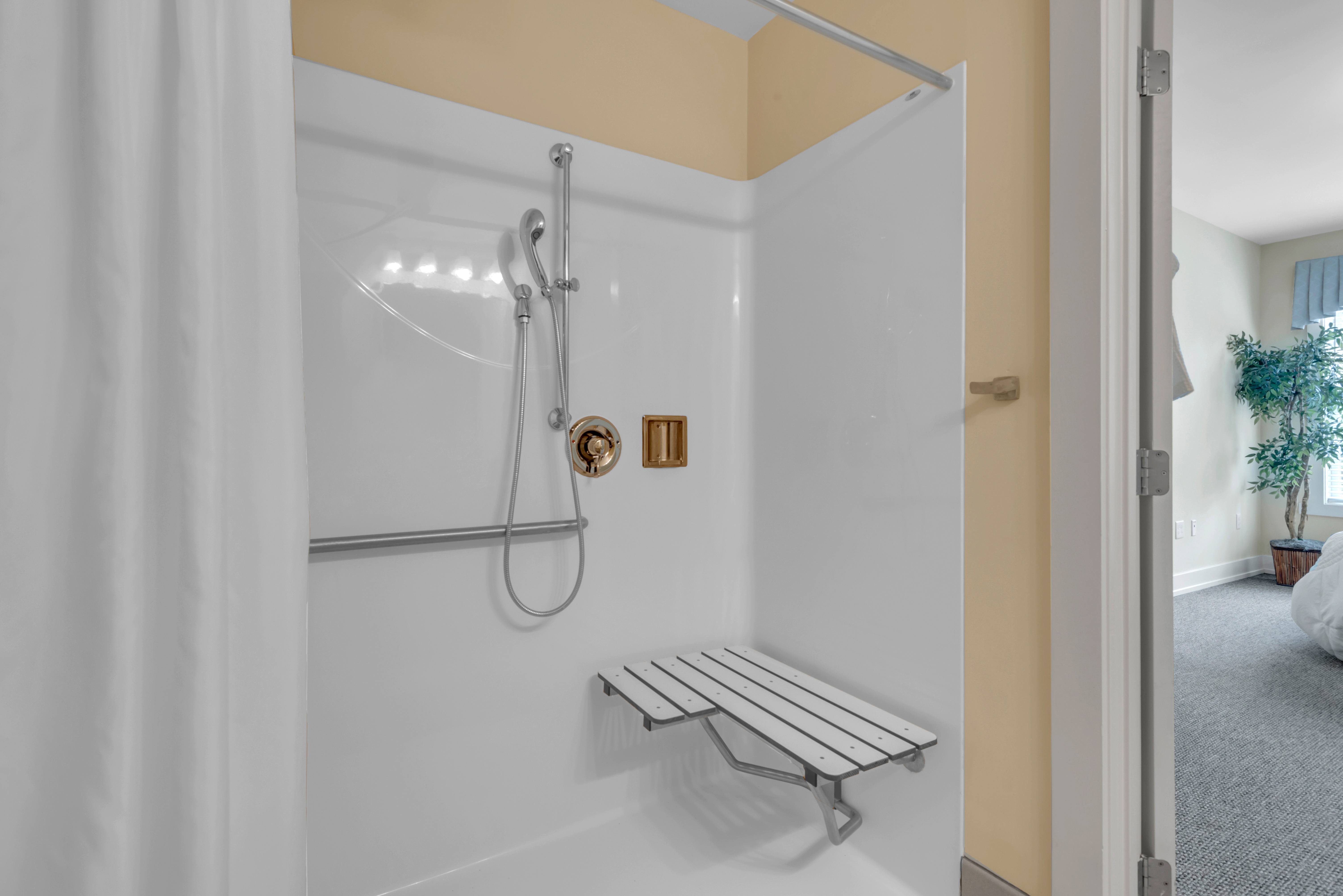 A white shower with a bench and a shower head.at Spring Arbor of Severna Park, Severna Park, Maryland