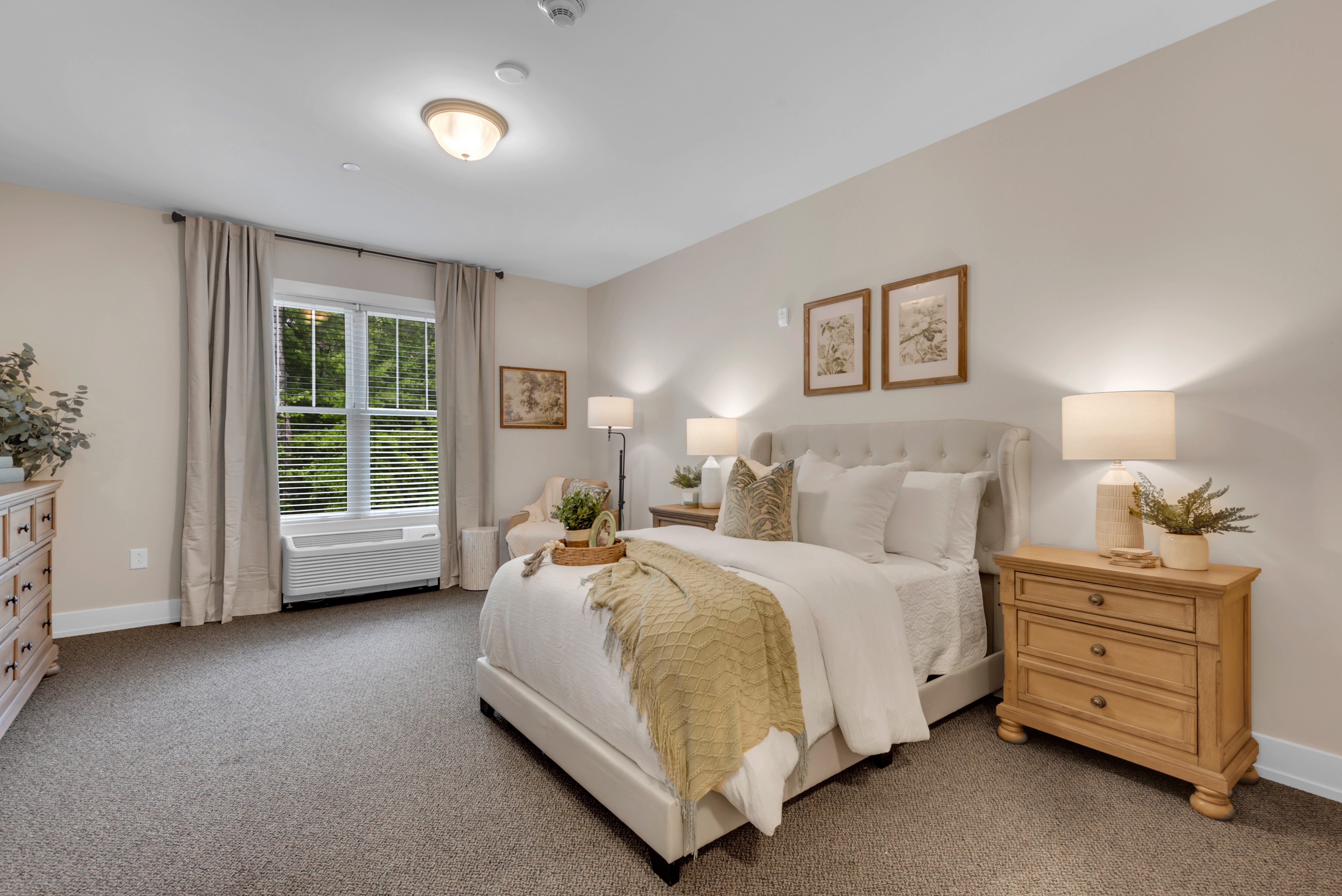 A bedroom with a large bed, a window with curtains, and a nightstand with a plant on it.at Spring Arbor of Severna Park, Severna Park, 21146