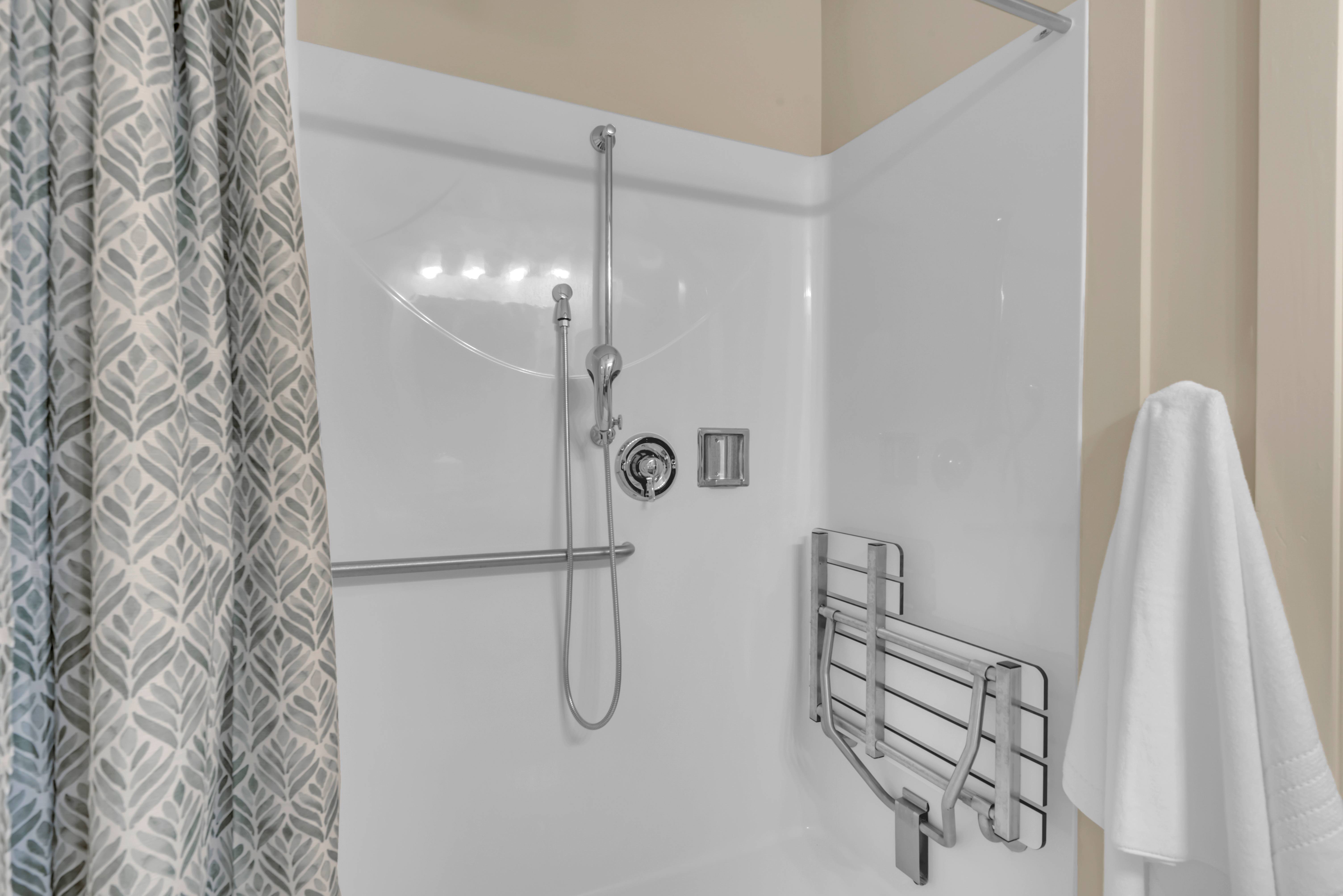 A shower with a curtain and a white towel hanging on the side.at Spring Arbor of Severna Park, Severna Park, MD
