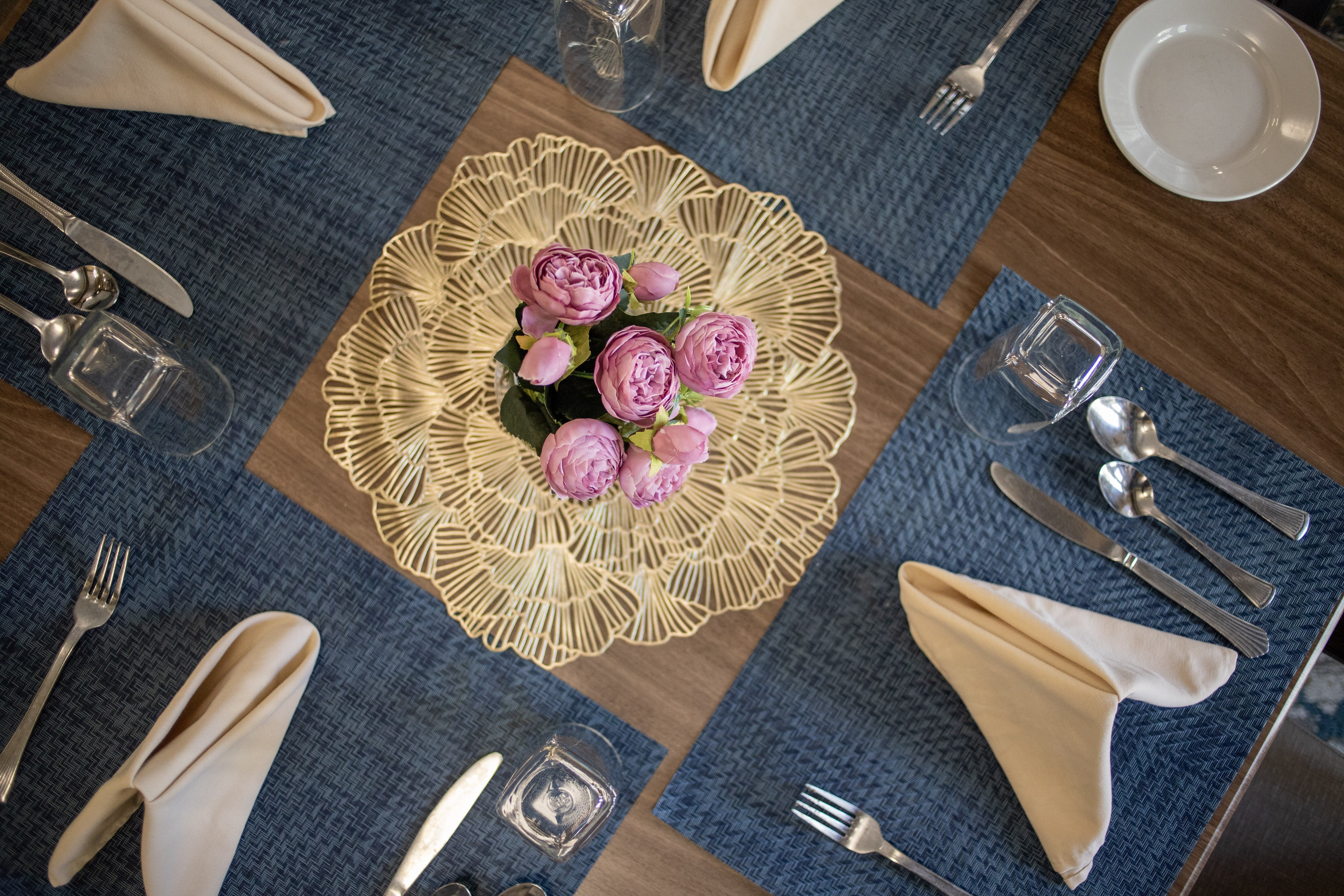 A table setting with a gold plate and pink flowers.at Spring Arbor of Williamsburg, Williamsburg, Virginia