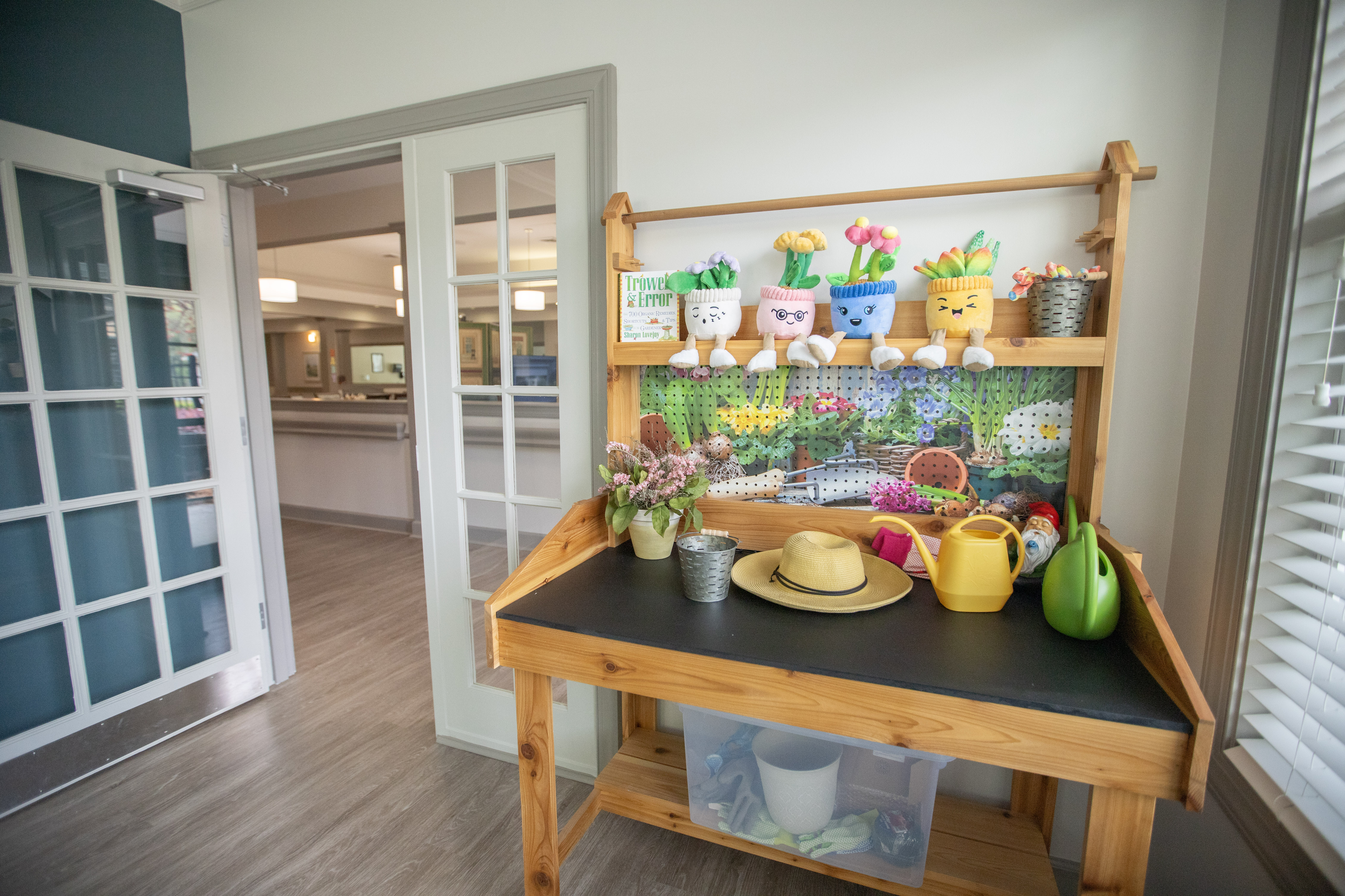 A wooden shelf with various potted plants and gardening tools.at Spring Arbor of Wilson, Wilson North Carolina