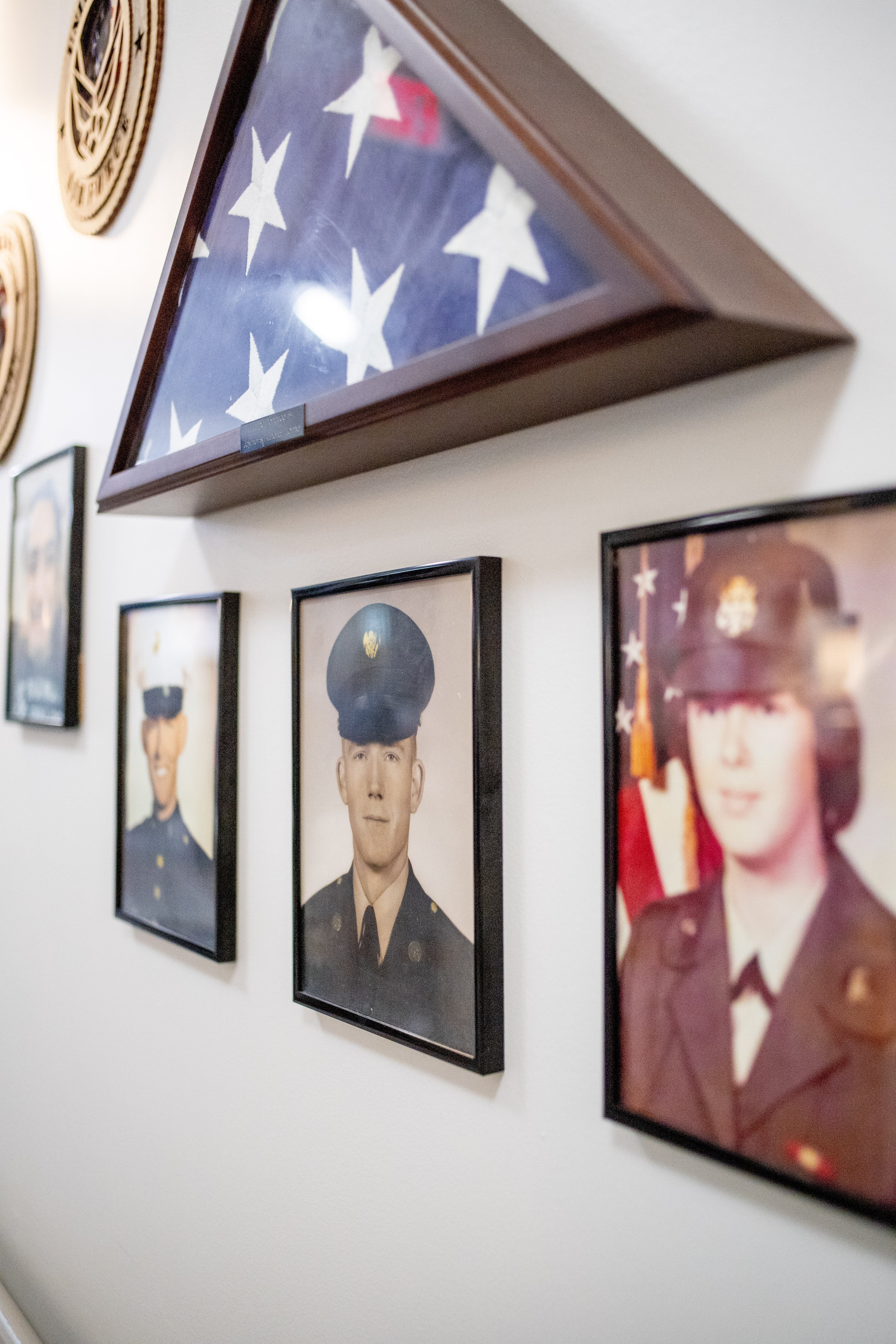 A wall with a framed American flag and three framed portraits of military personnel.at Spring Arbor of Wilson, Wilson North Carolina