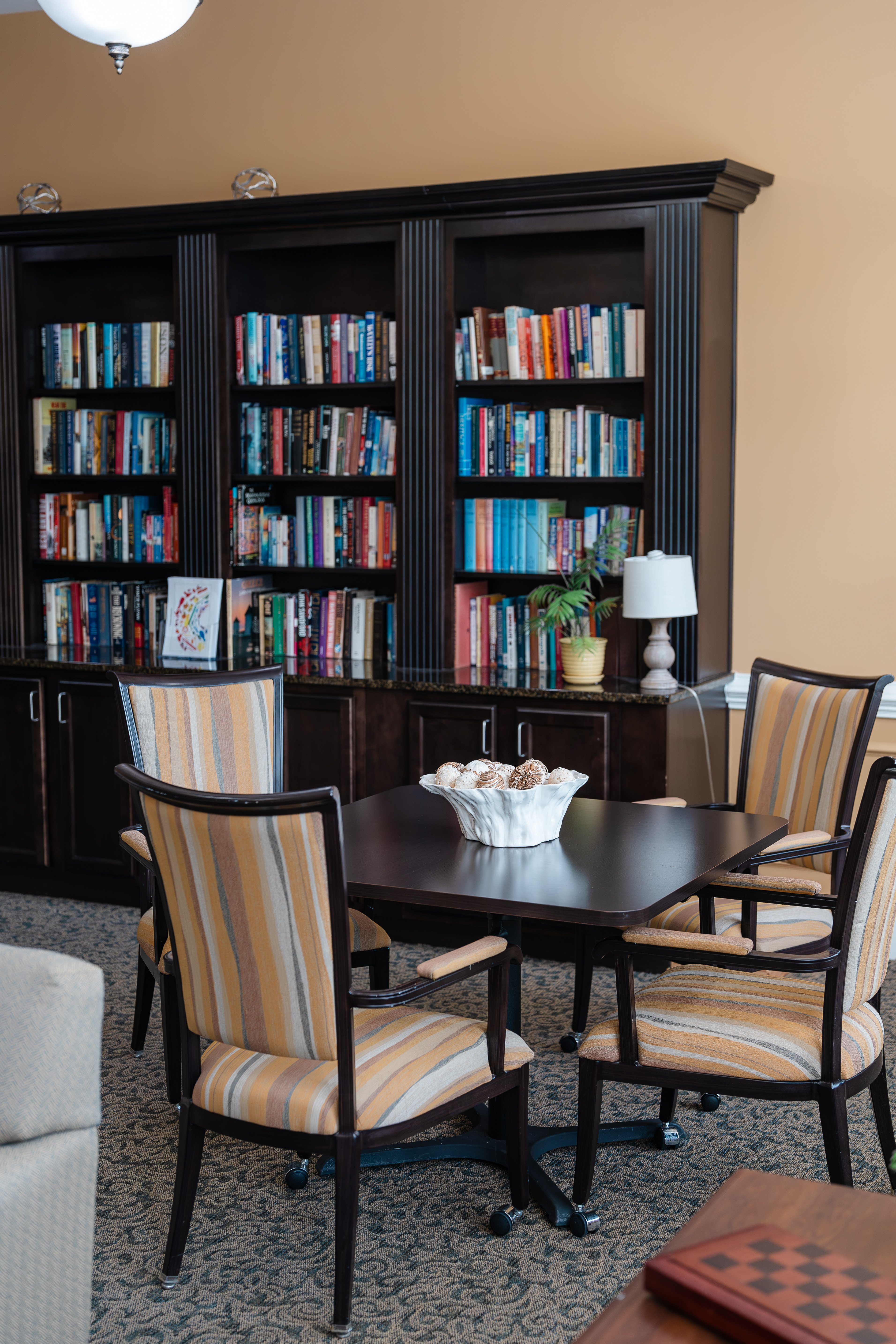 A room with a table, chairs and a bookshelf at Spring Arbor of Cary in Cary, NC