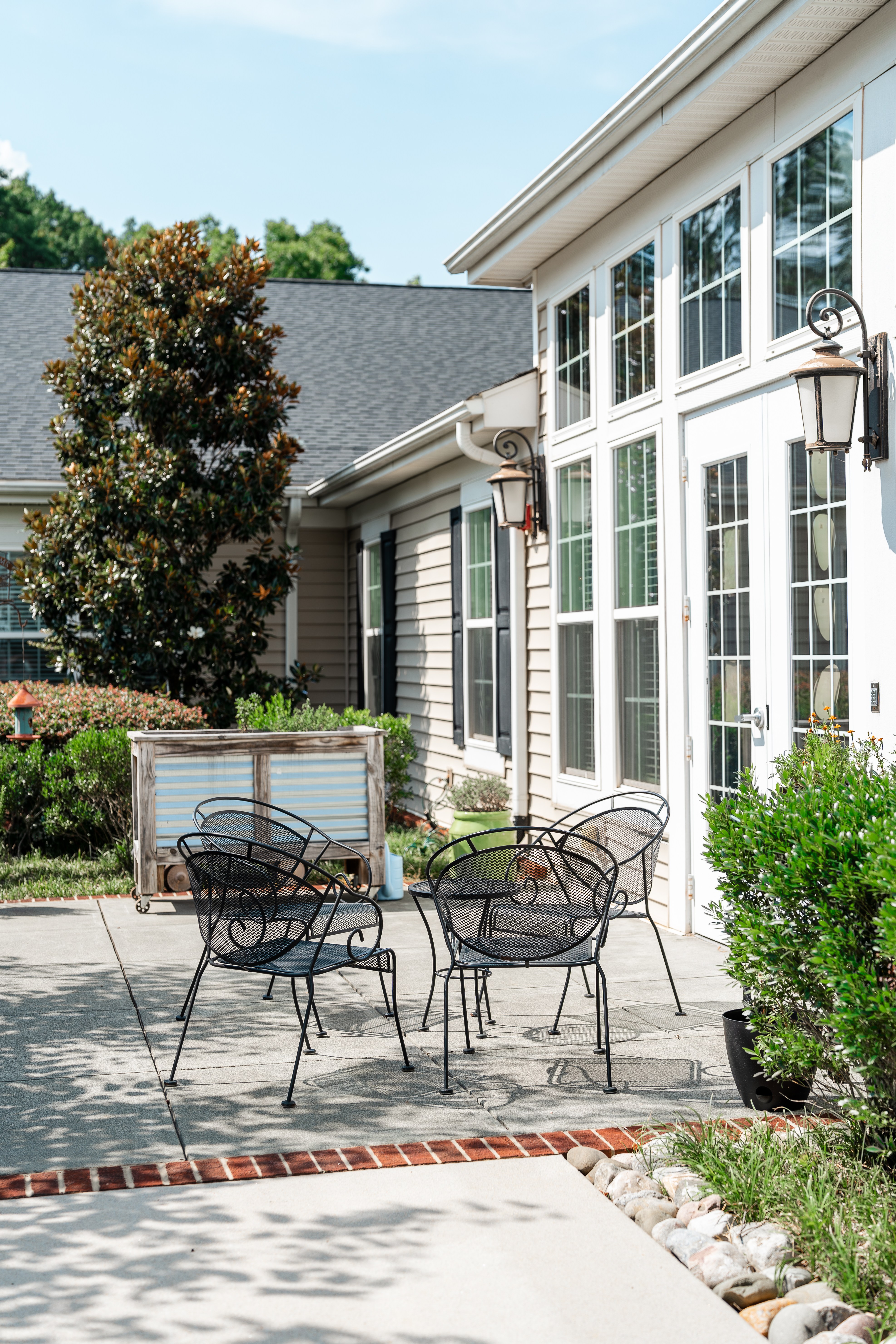 A patio with a table and chairs is in front of a house at Spring Arbor of Cary in Cary, NC