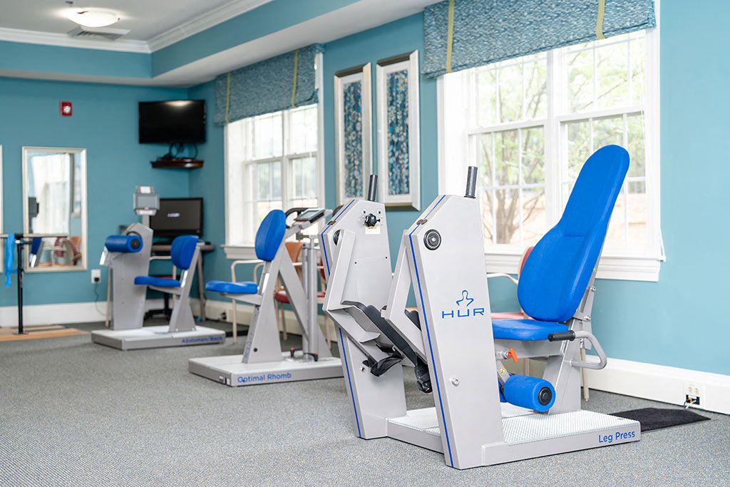 Gym with cardio machines and chairs in a room with windows at Spring Arbor of Rocky Mount
