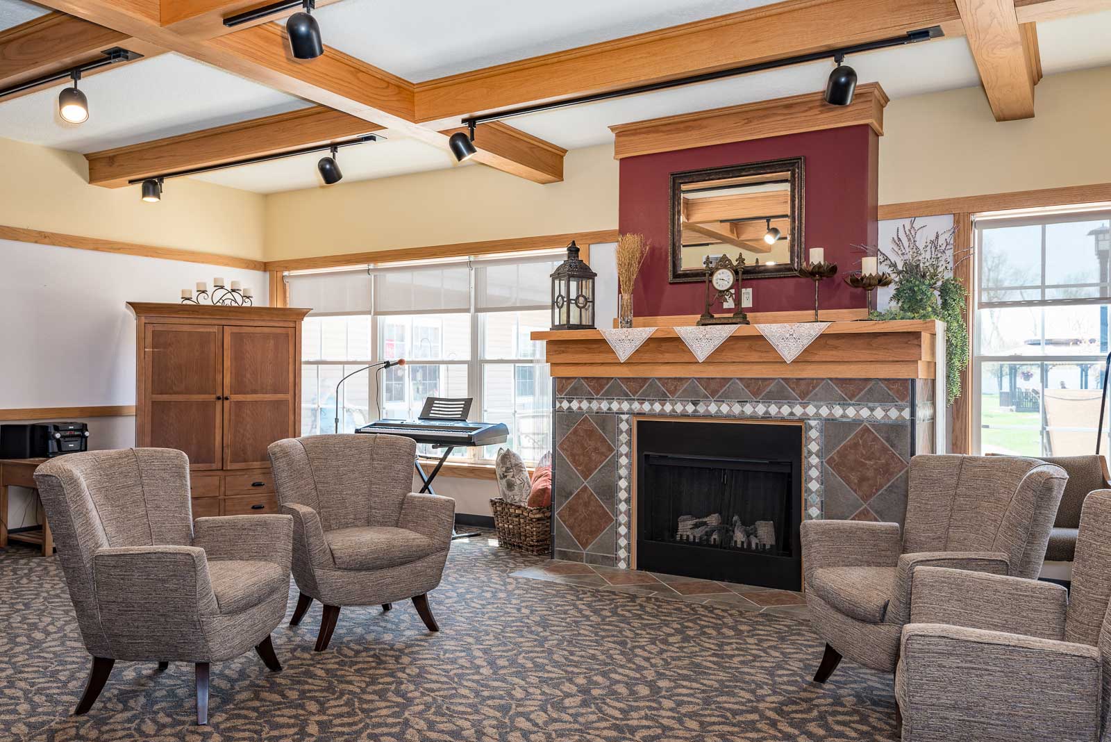 A living room with a fireplace and chairs at Windsor Manor Grinnell, Grinnell, IA