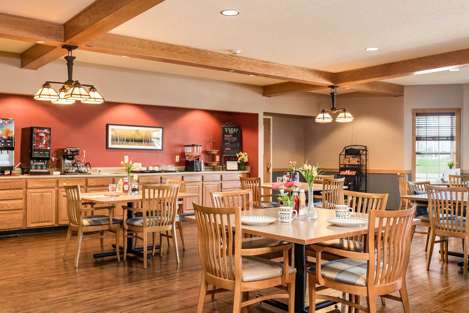 A restaurant with wooden chairs and tables at Windsor Manor Indianola, Indianola, IA