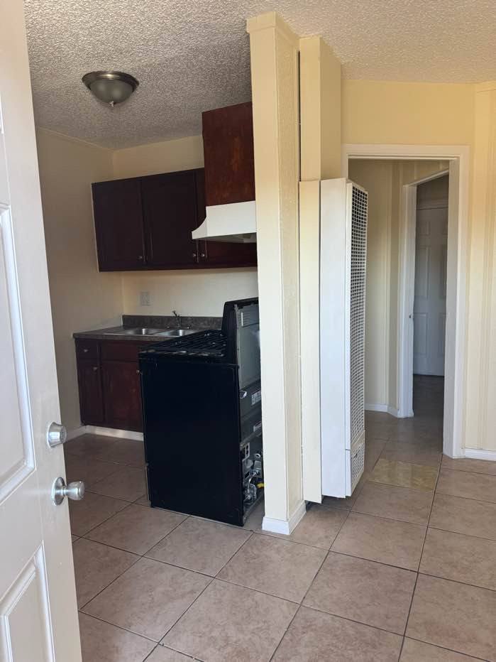 A kitchen with a black fridge and white cabinets.