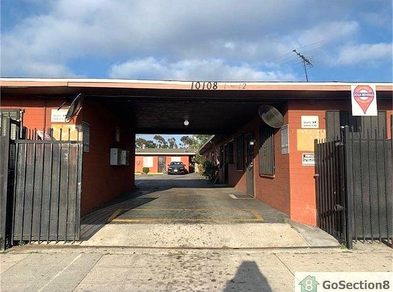 A red building with a black gate in front of it.