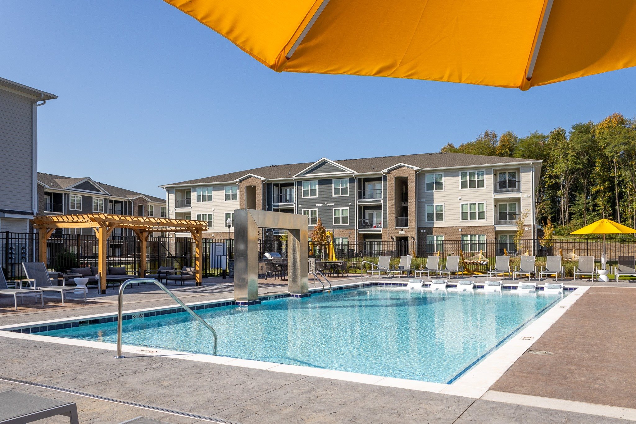 A swimming pool with a yellow umbrella and a building in the background.