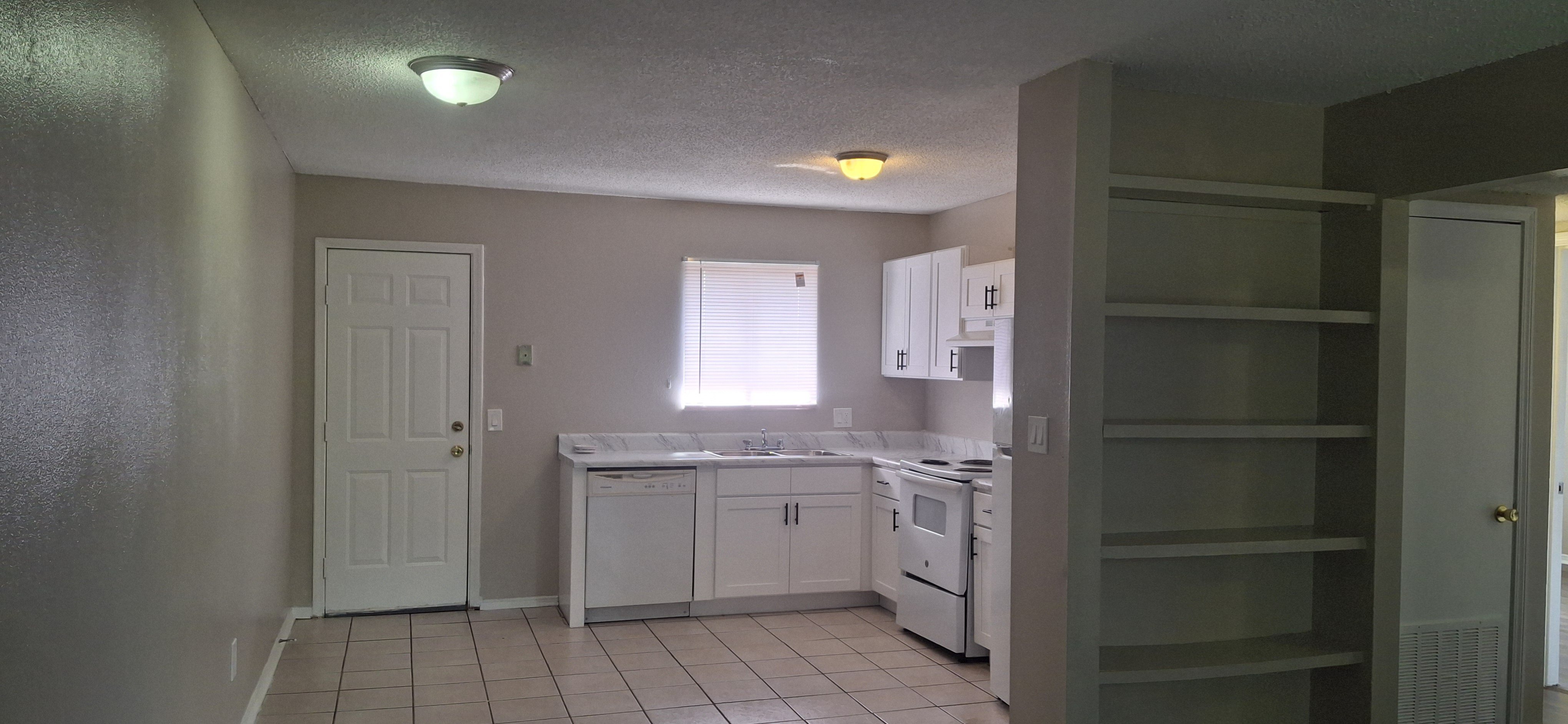 A kitchen with white cabinets and a white door.