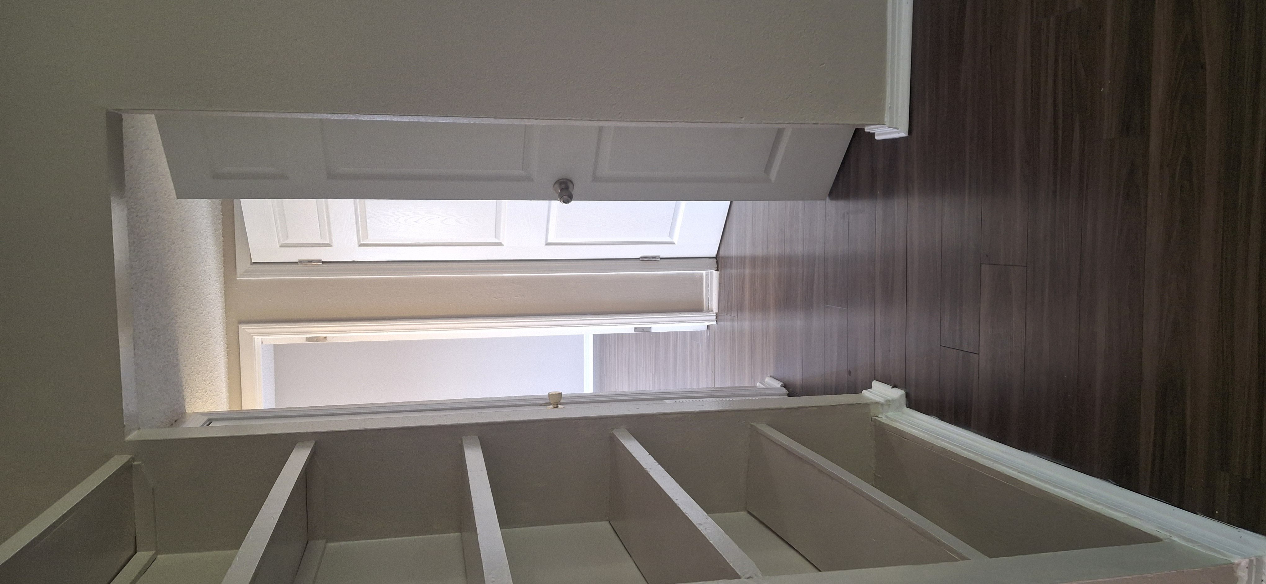 A room with a window and wooden paneling on the wall.