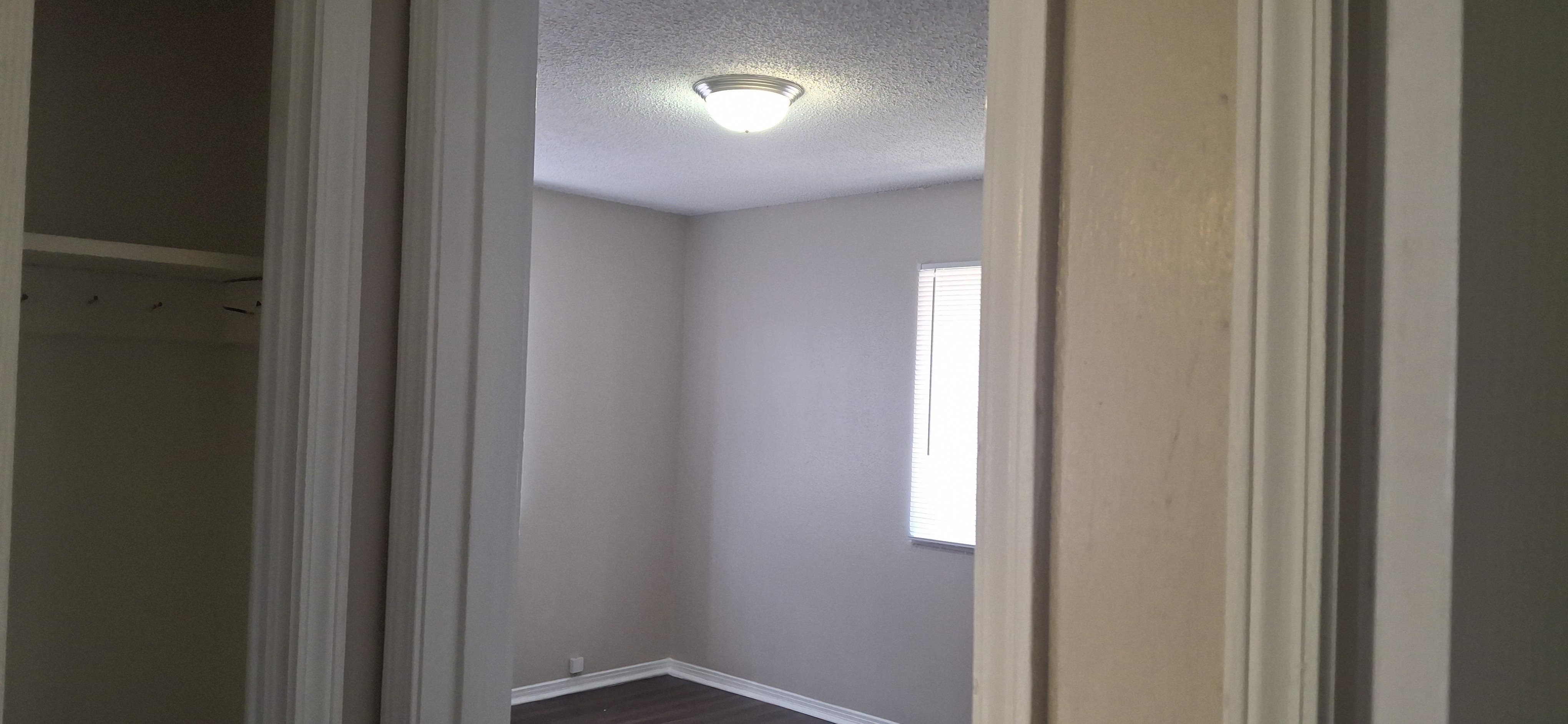 A white door is open to a room with a light on the ceiling.