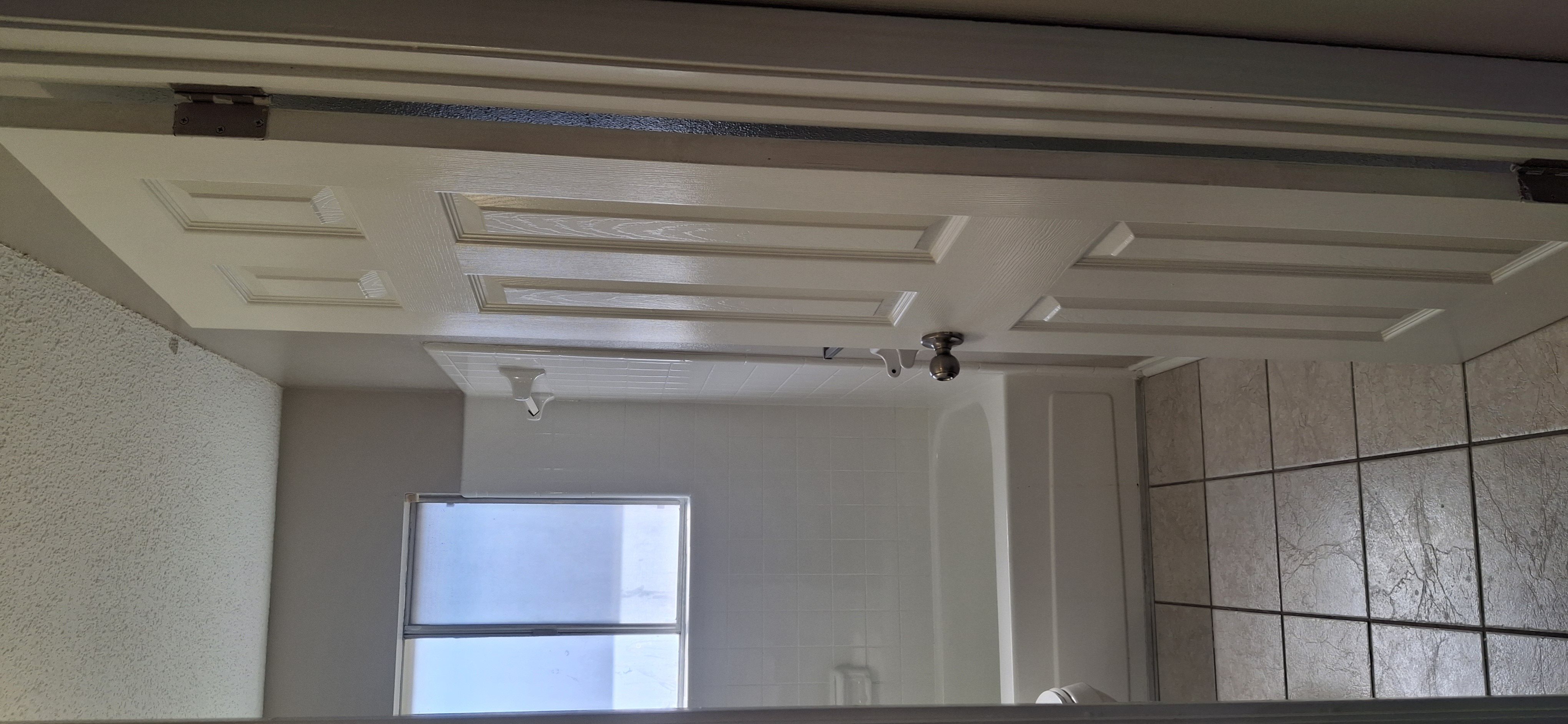 A white ceiling with a vent and a window.