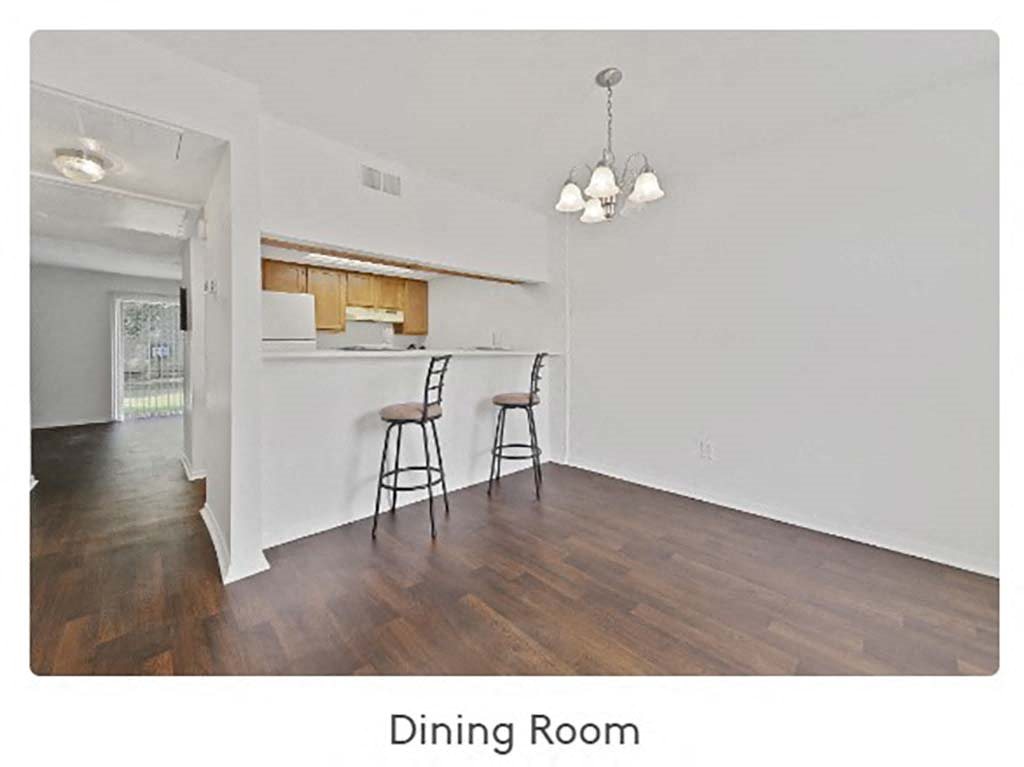 a dining room with a table and chairs and a kitchen in the background