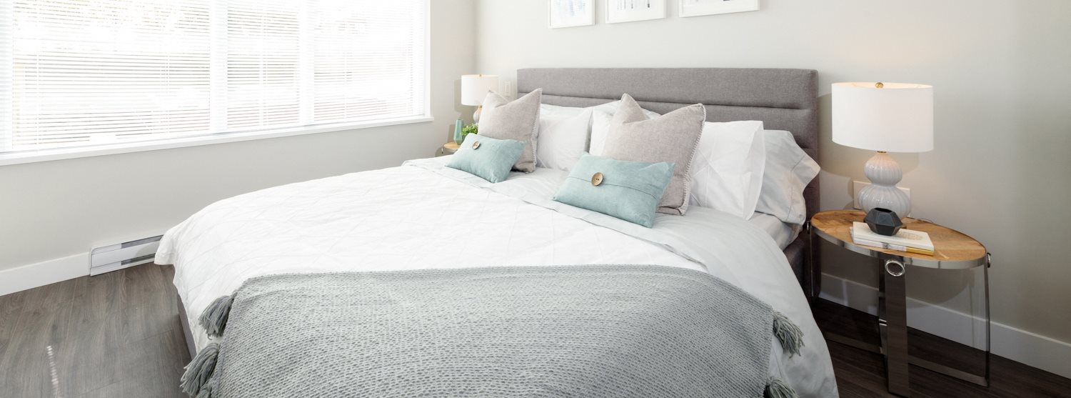 White bed with grey throw blanket and light blue pillows