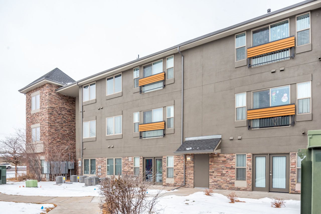 Exterior view of Connections at 6th Exterior view of Connections at 6th, dark grey stucco with rock masonry on first floor, juliet balconies, and patio on ground level